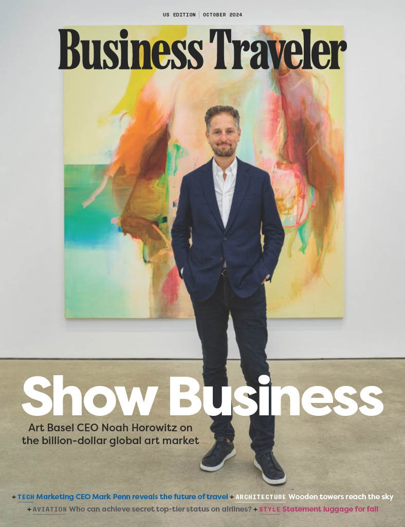 The cover of Business Traveler magazine, October 2024 issue. Features a man in a navy suit standing in front of an abstract colorful artwork. The headline reads 'Show Business' and mentions Art Basel CEO Noah Horowitz discussing the global art market.