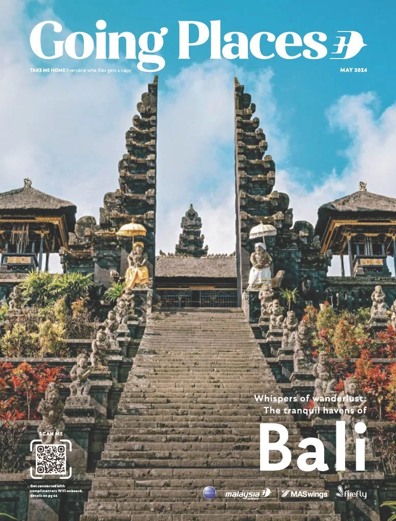 A temple in Bali with stone steps leading up to the entrance, flanked by stone sculptures and traditional structures, under a cloudy sky.