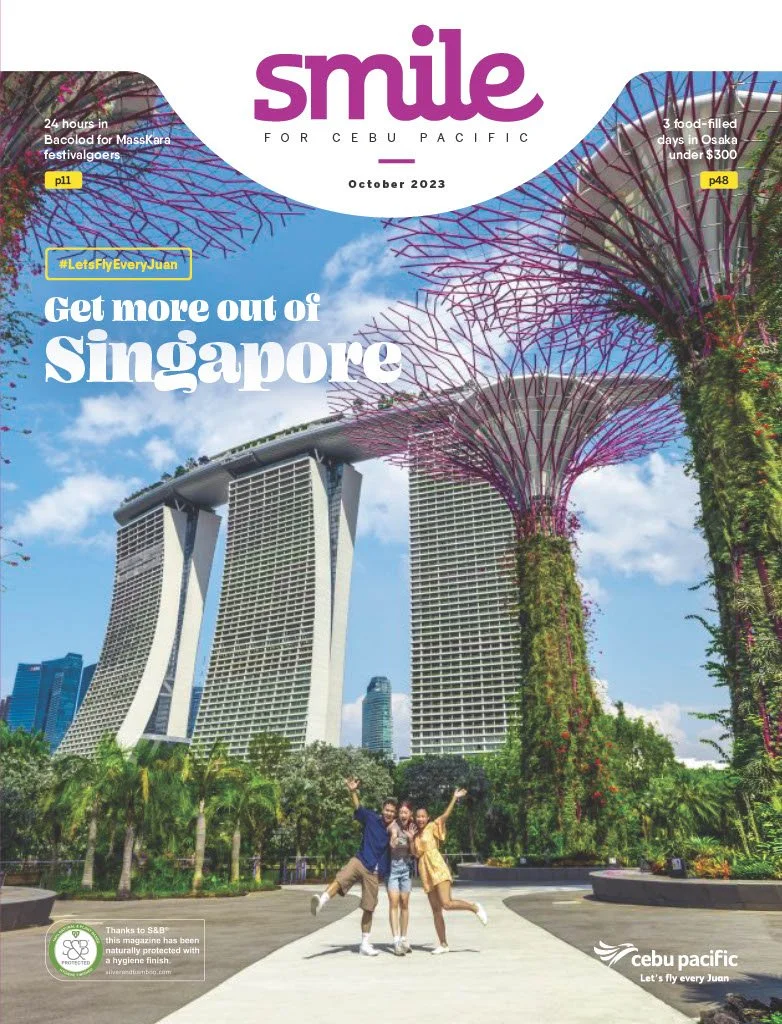 Three people happily posing in front of the Marina Bay Sands and the Supertree Grove at Gardens by the Bay in Singapore.