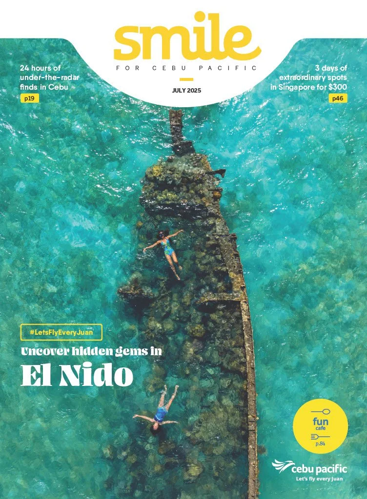 Aerial view of two people snorkeling or swimming over a submerged coral reef or shipwreck in clear blue water near Cebu, Philippines.