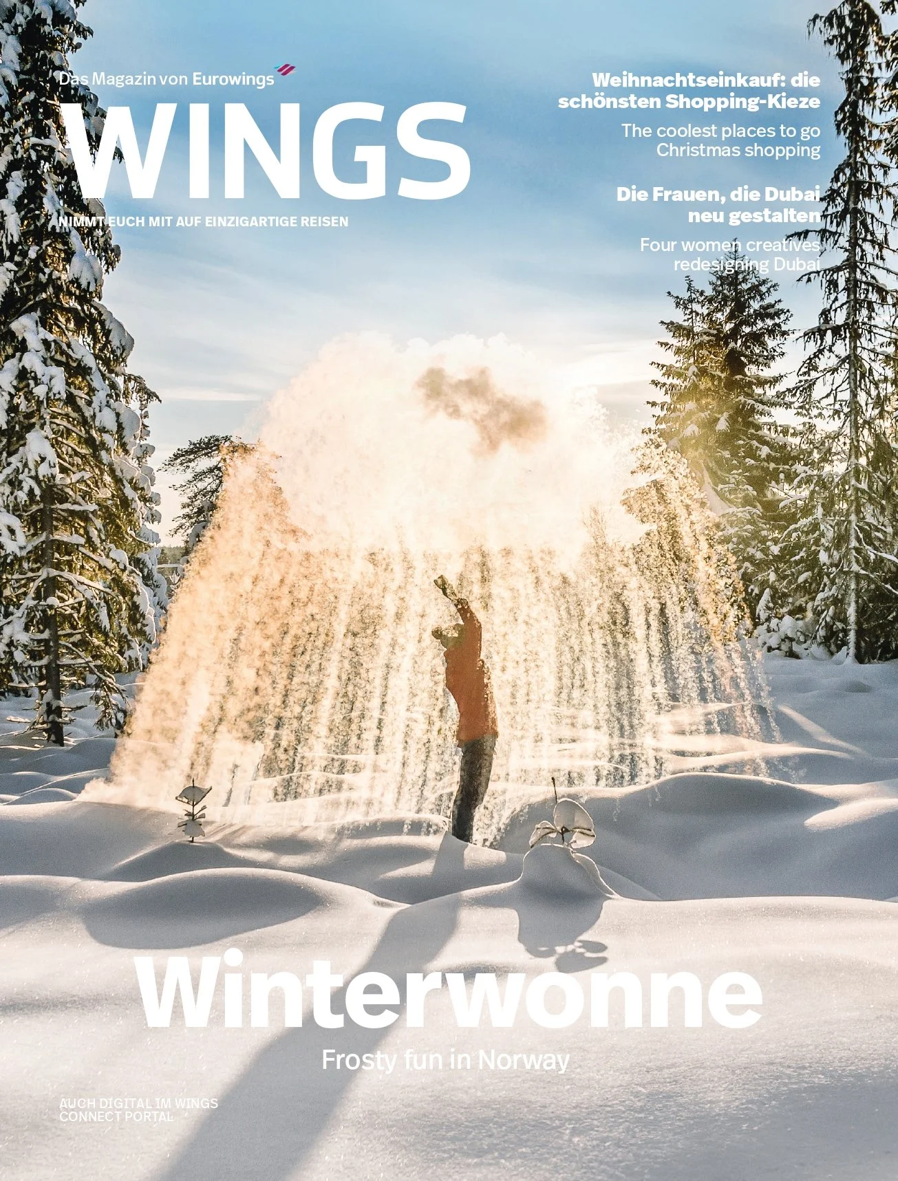 A person in winter clothing standing in a snowy landscape, playing with a water fountain that sprays water into the air, with snow-covered trees in the background and sunlight.