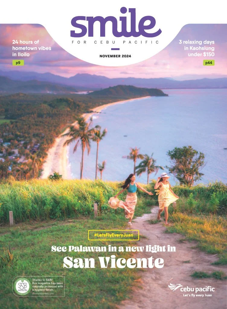 Cover of a magazine titled 'smile' featuring a coastal landscape with two women holding hands and running along a grassy trail near the ocean, with mountains in the background. Highlighted articles mention hometown vibes in Iloilo and relaxing days in Kaohsiung. Main headline promotes visiting Palawan in San Vicente.