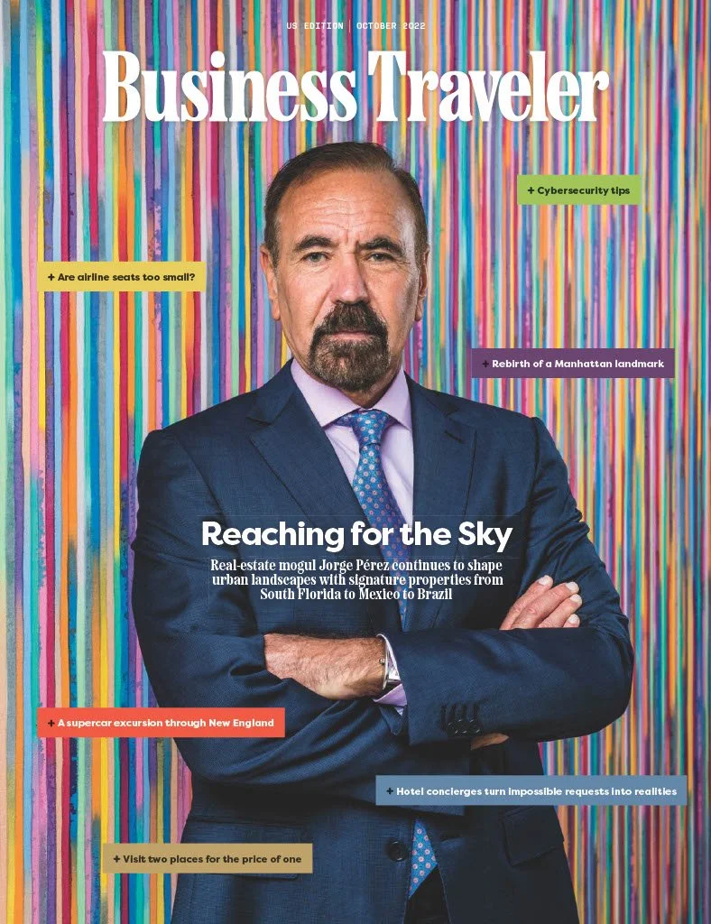 Cover of Business Traveler magazine featuring Jorge Pérez in a dark suit and tie, with a background of colorful vertical stripes, discussing urban real estate investments