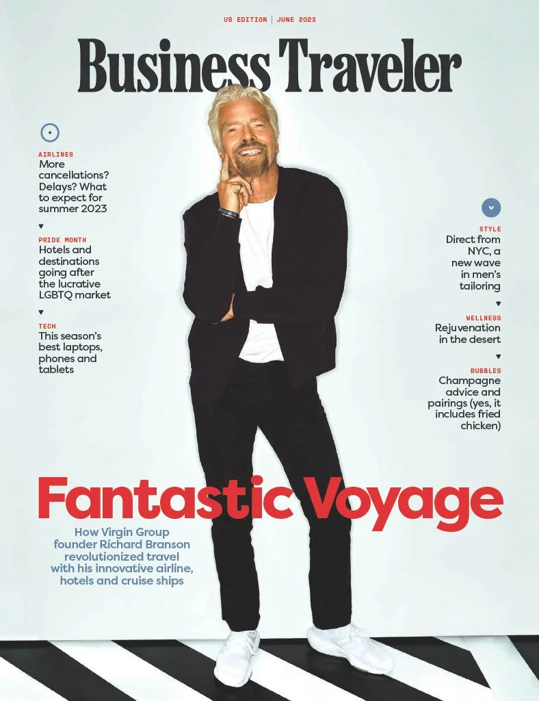 Cover of Business Traveler magazine, June 2023 issue, featuring a smiling man with white hair and beard, wearing a black blazer, white t-shirt, black pants, and white sneakers, standing against a light-colored background with black and white striped floor.