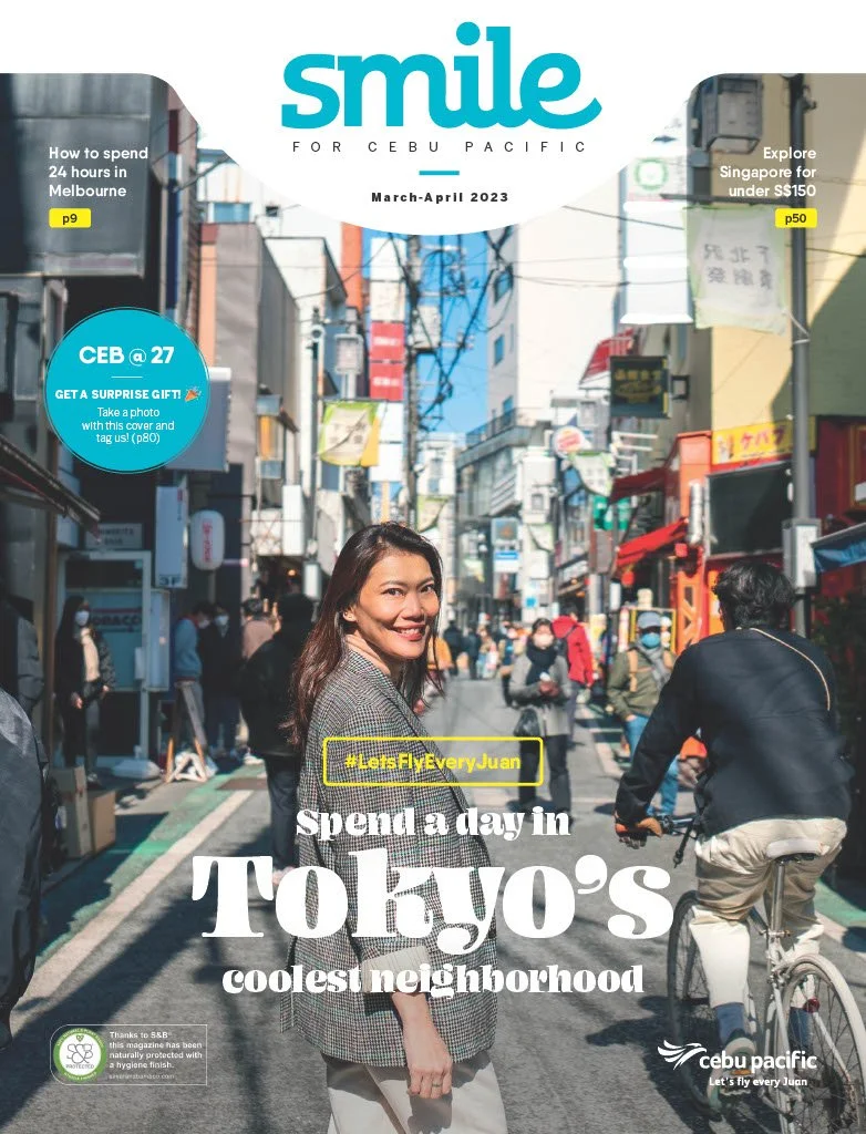 Cover page of a magazine titled 'Smile for Cebu Pacific' from March-April 2023, featuring a woman smiling in a busy Tokyo street viewed from the front, with pedestrians and cyclists in the background, advertising Tokyo's neighborhoods.