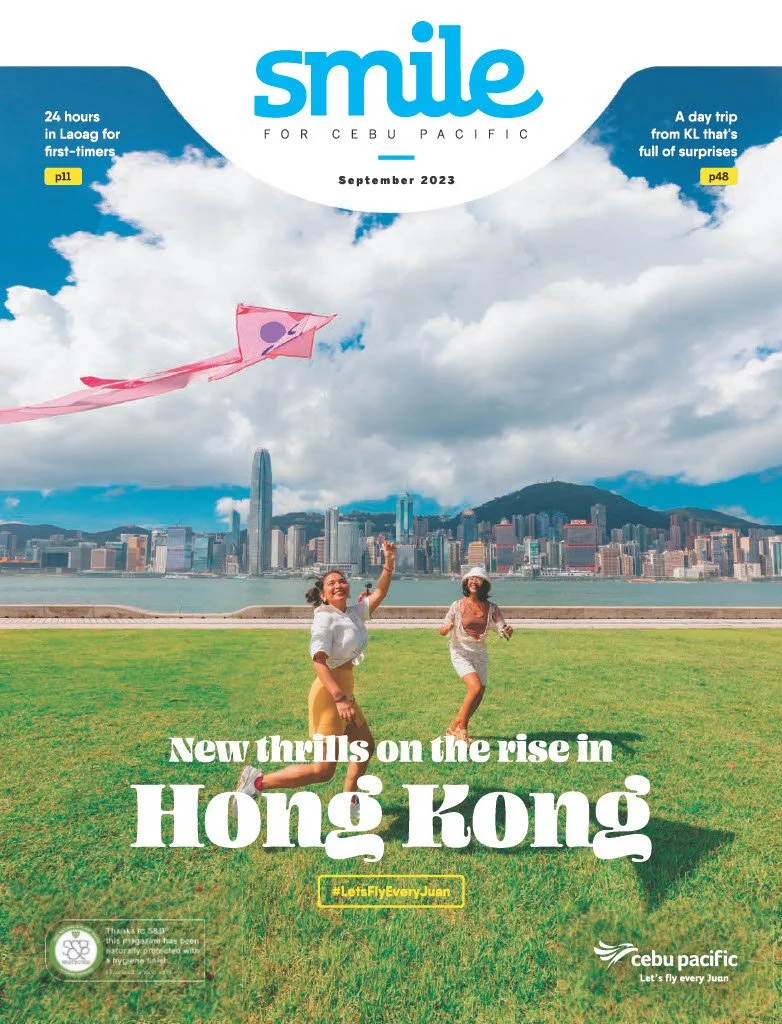 A city skyline of Hong Kong with two women flying a pink kite in a grassy park in the foreground. The sky is partly cloudy, and the headline mentions the rise of Hong Kong.
