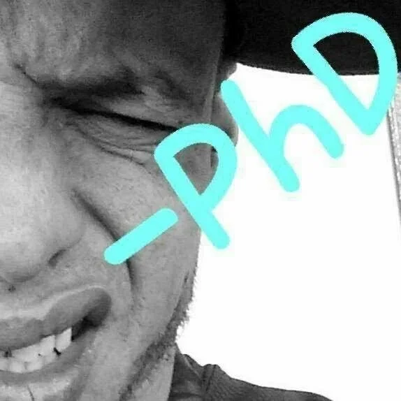 Close-up of a smiling man's face with eyes closed, wearing a cap, with the word '-Phe' written in blue across the image.