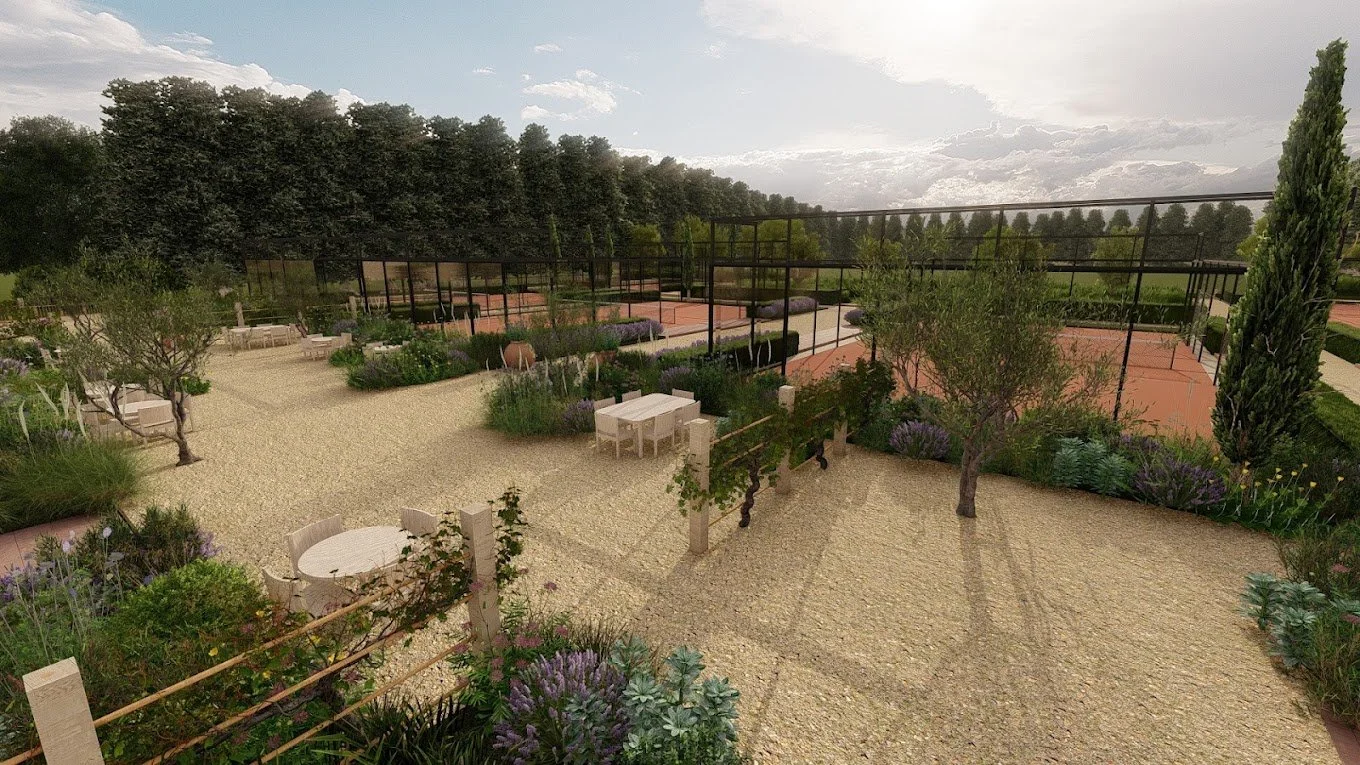 A garden area with outdoor tables and chairs, trees, flowering plants, and tennis courts in the background under a partly cloudy sky.