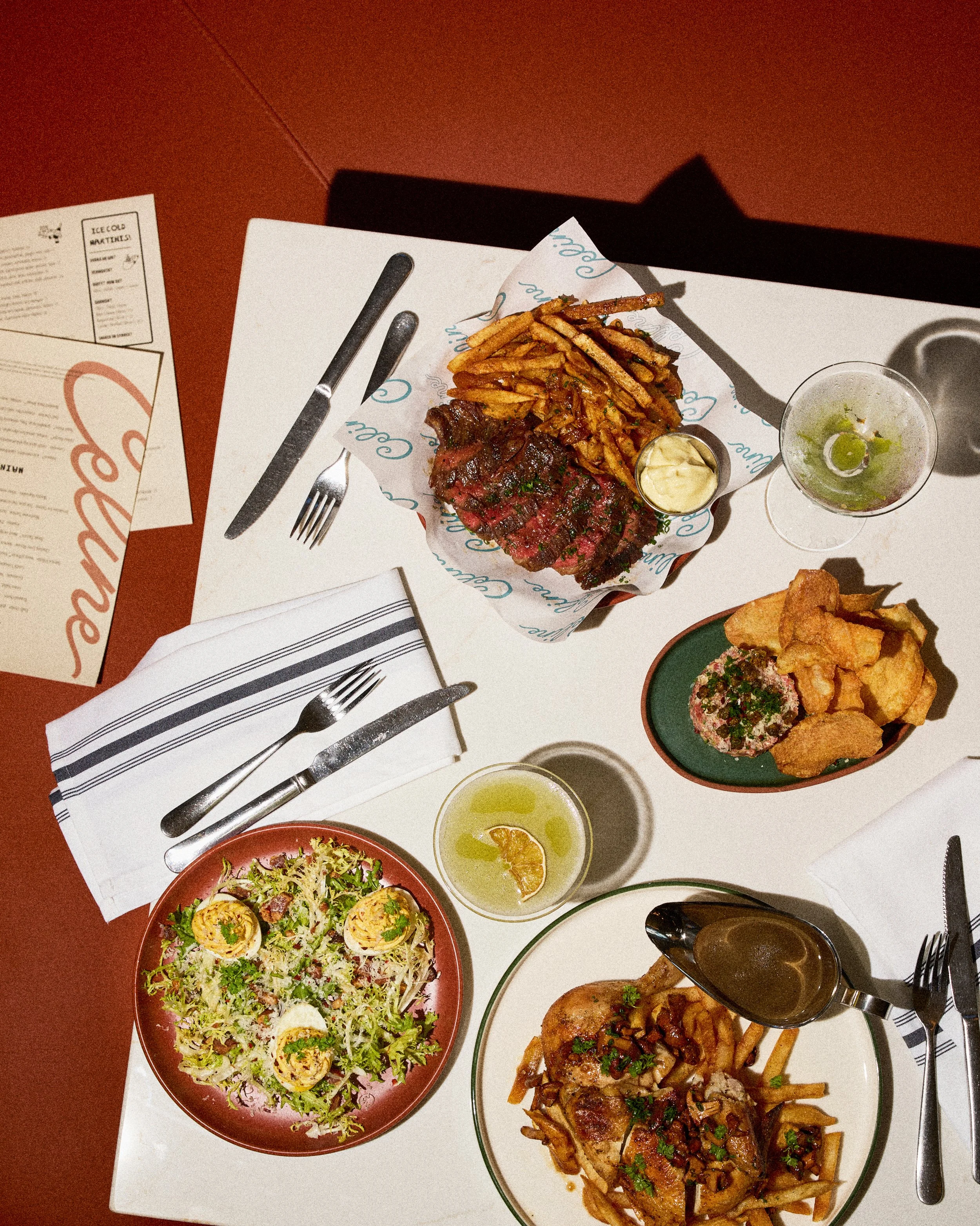 Photo by Emily Kan displays a salad, roasted chicken, cocktails and steak frites at Celine