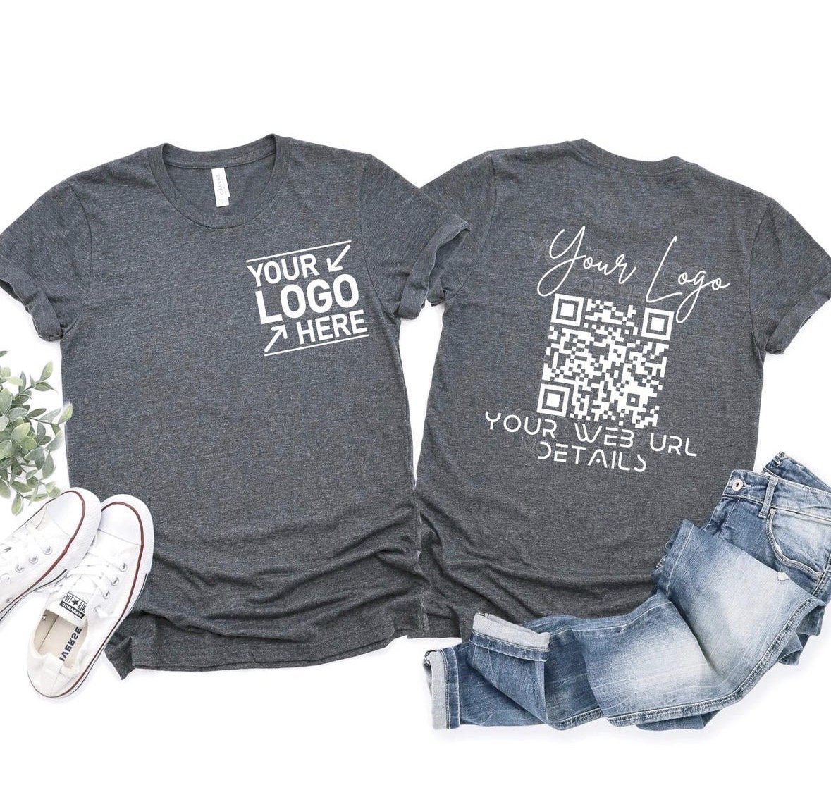 Two dark gray T-shirts, one showing 'Your Logo Here' and the other with 'Your Logo,' a QR code, and space for web URL details. Also shown are a pair of white sneakers with red stripes, a pair of blue jeans, and a small green plant.