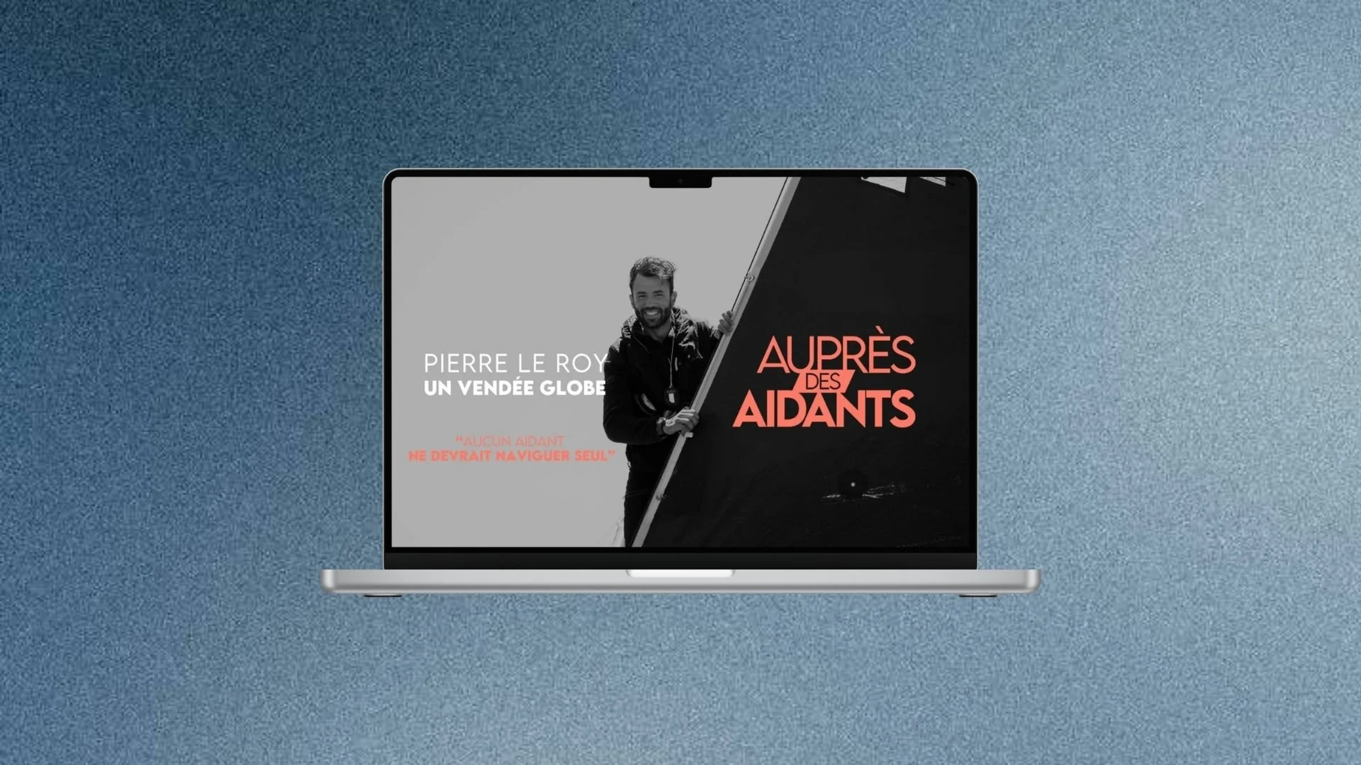 Une image d'un ordinateur portable affichant la couverture d'un livre ou d'une vidéo intitulée 'Après des Aidants' avec une photo en noir et blanc d'un homme souriant, tenant un drapeau. Le fond de l'image est bleu avec une texture de dégradé.