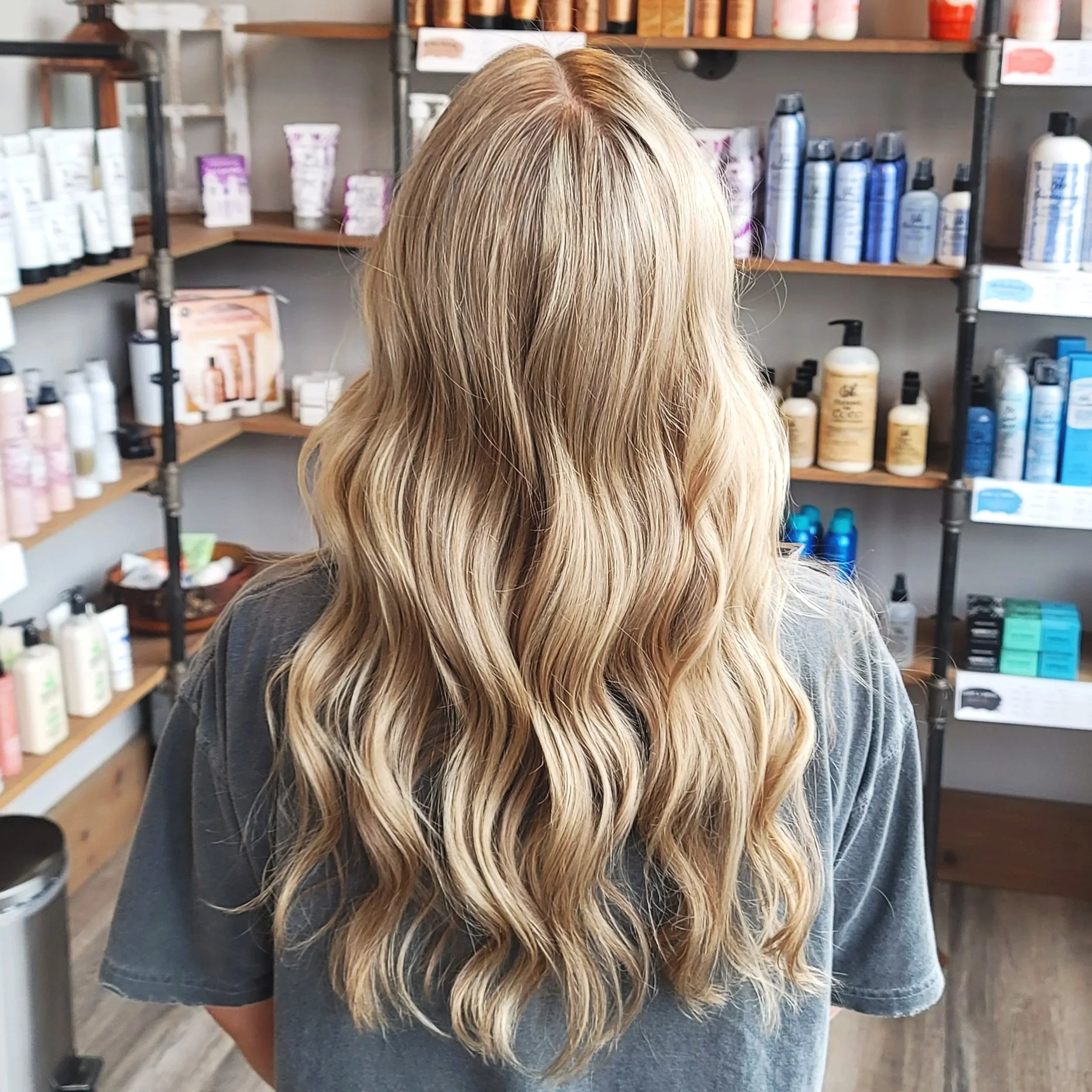 Back of a woman with long, wavy blonde hair in a haircare store.