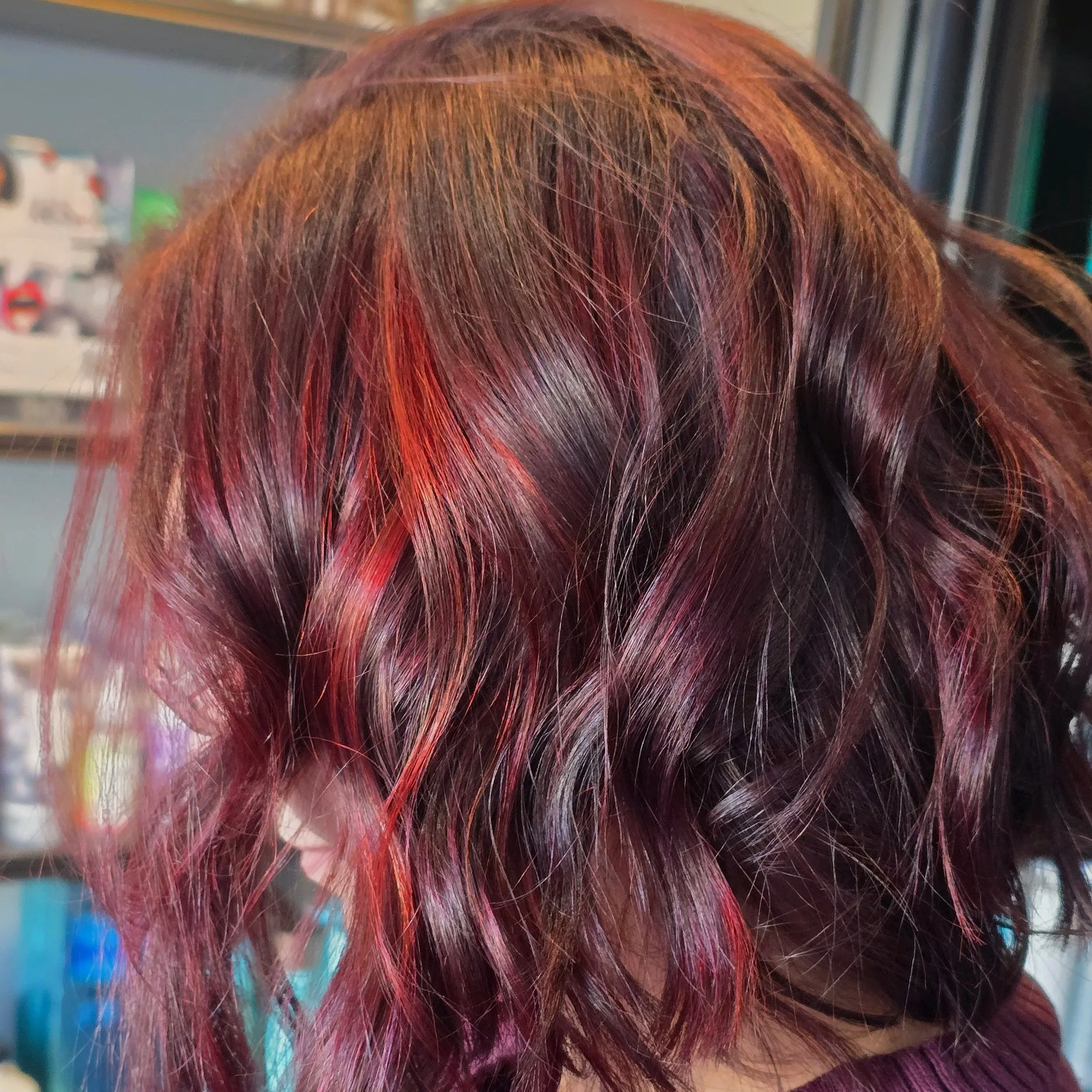 Close-up of wavy, layered hair with multiple shades of red and purple.
