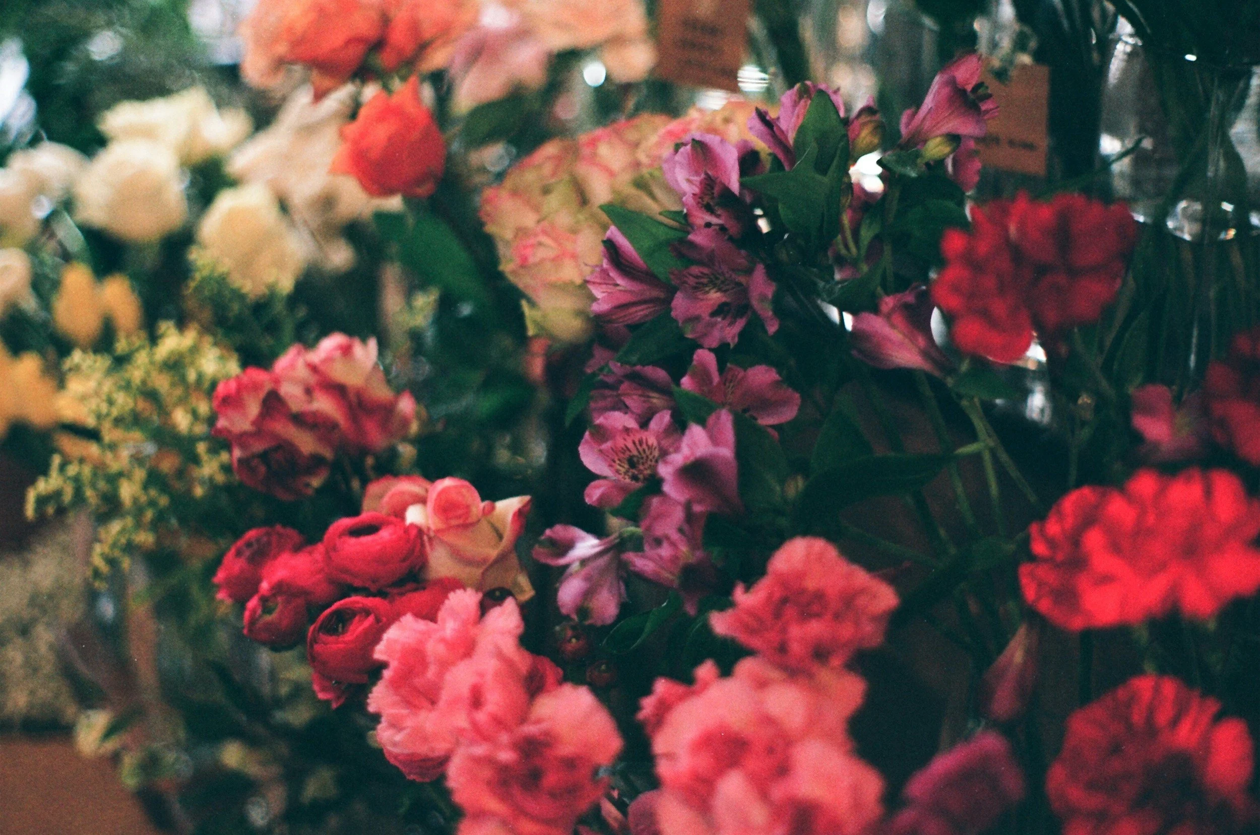 A variety of colorful flowers including pink, red, yellow, and orange blooms in a floral arrangement.