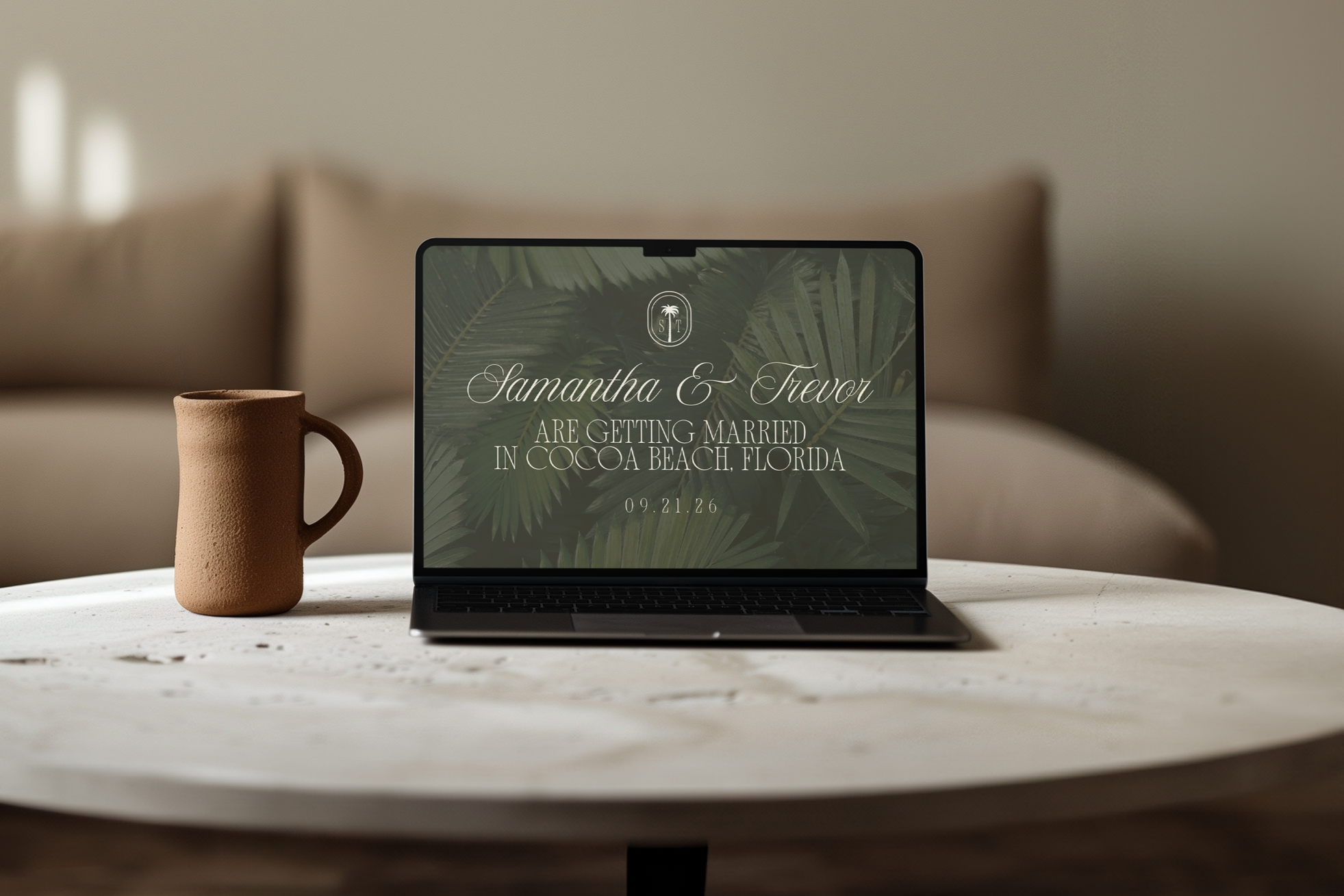 Laptop on a white table displaying an invitation to a wedding of Samantha and Trevor in Cocoa Beach, Florida, with a background of tropical leaves. A brown textured mug is next to the laptop.
