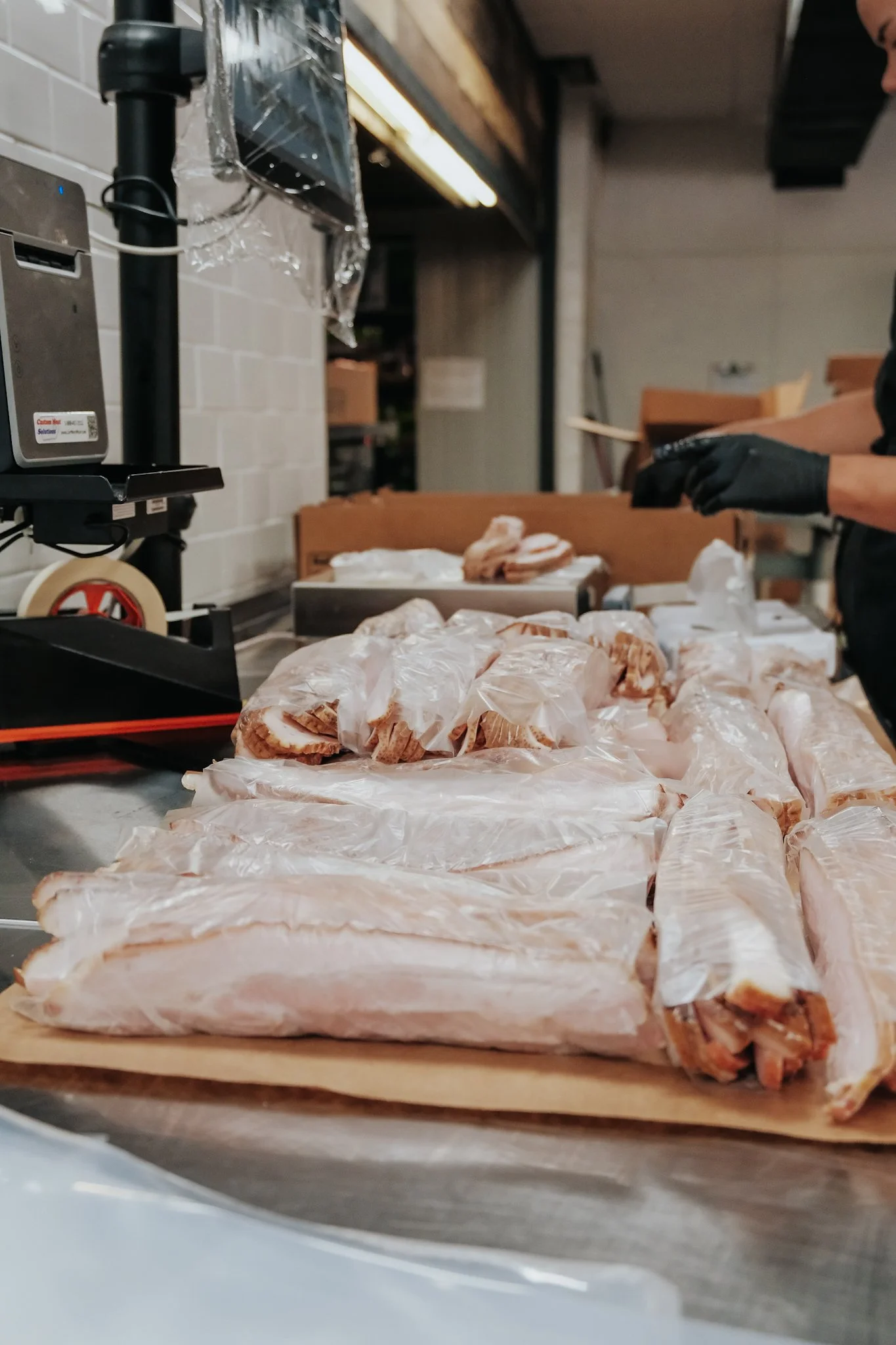 Raw pork roast wrapped in plastic on a wooden cutting board in a kitchen preparing to cook.