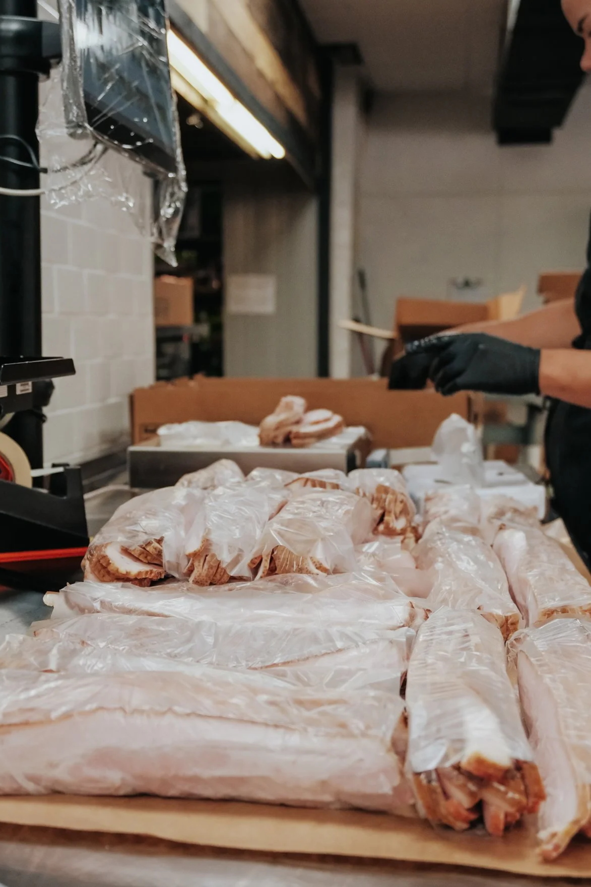 Tray of vacuum-sealed raw meat cuts on a wooden surface in a butchery or meat preparation area.