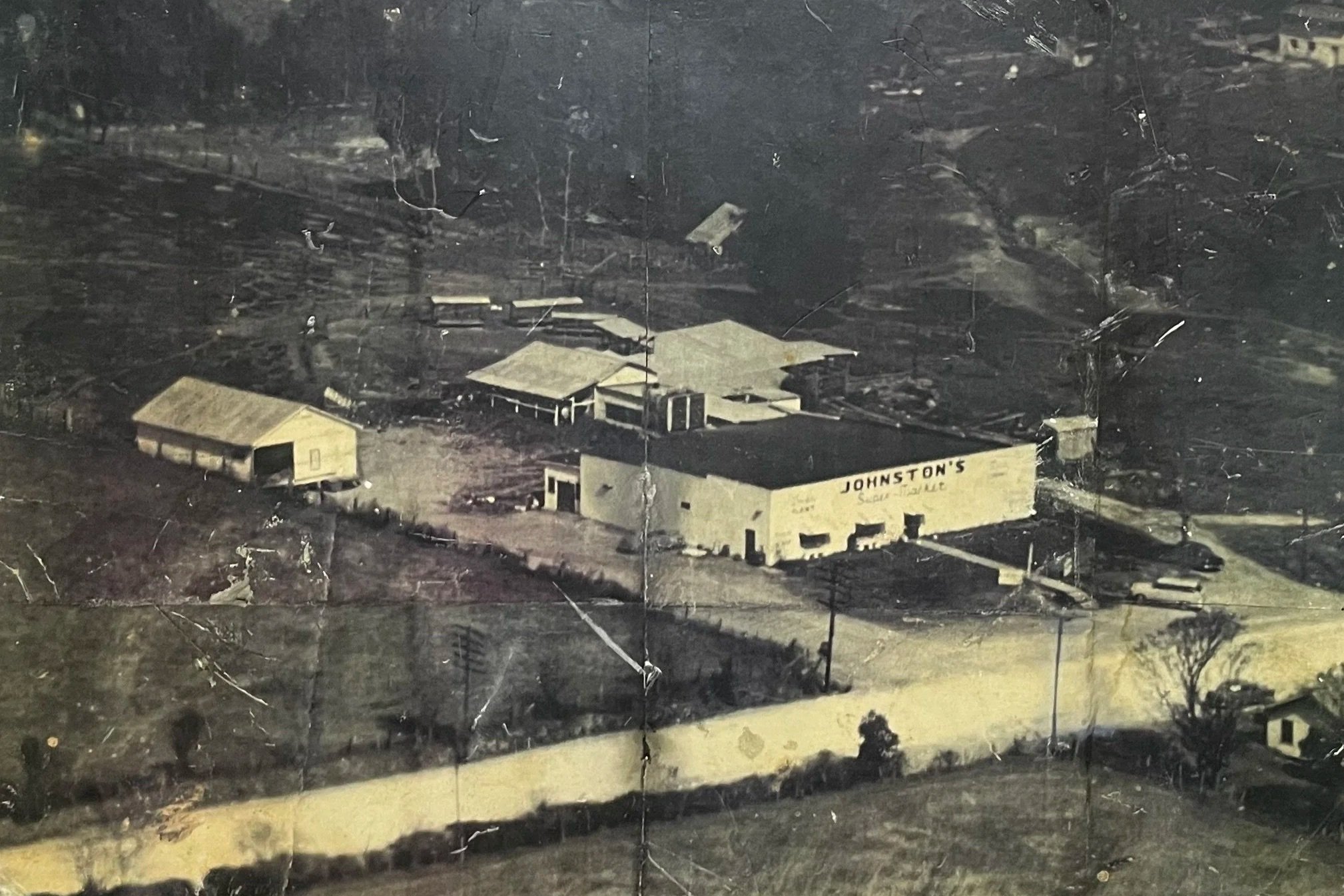 A building labeled 'Johnston's' with a parking lot and surrounding area, viewed from above.