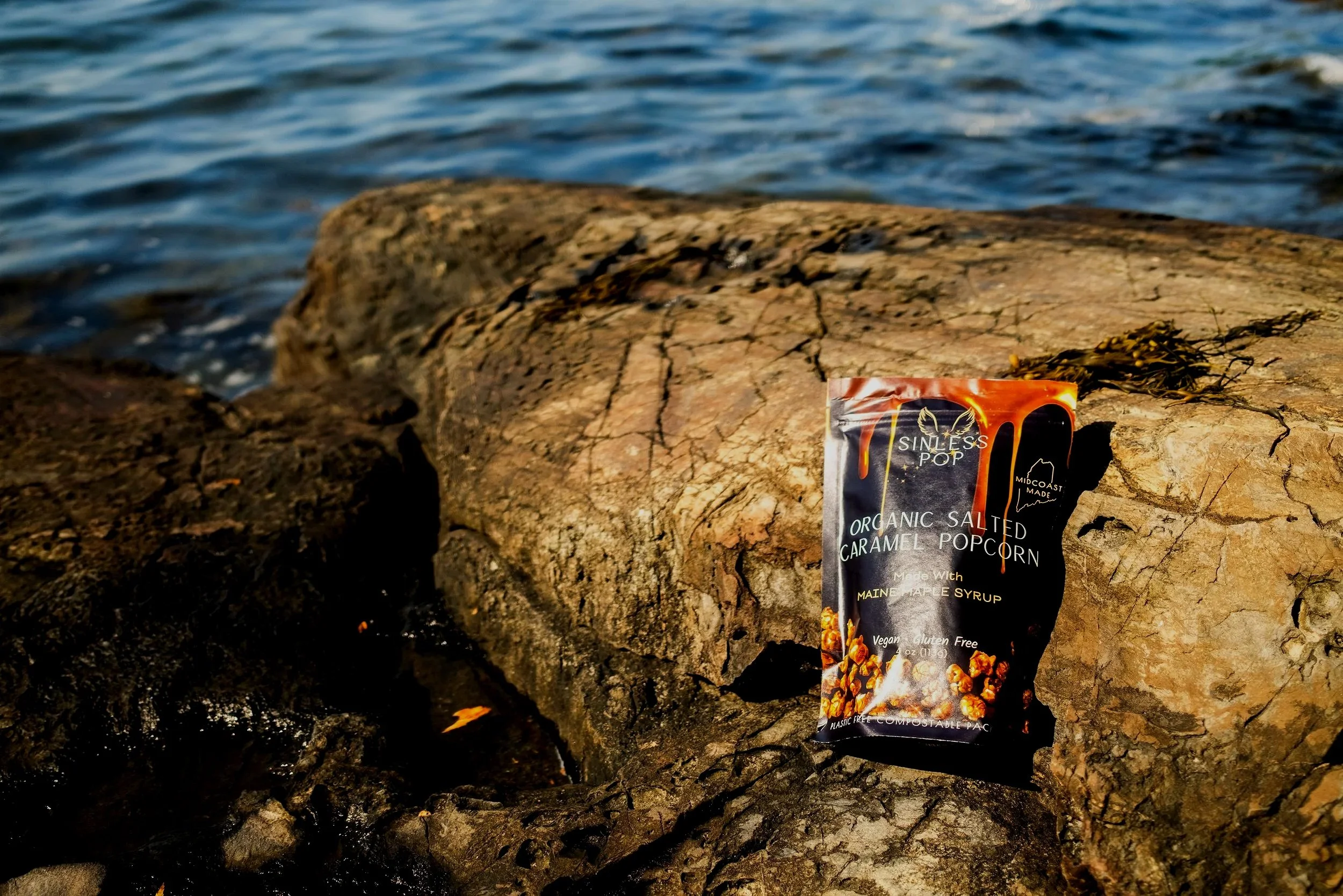 A bag of organic salted caramel popcorn positioned on a rock in Maine