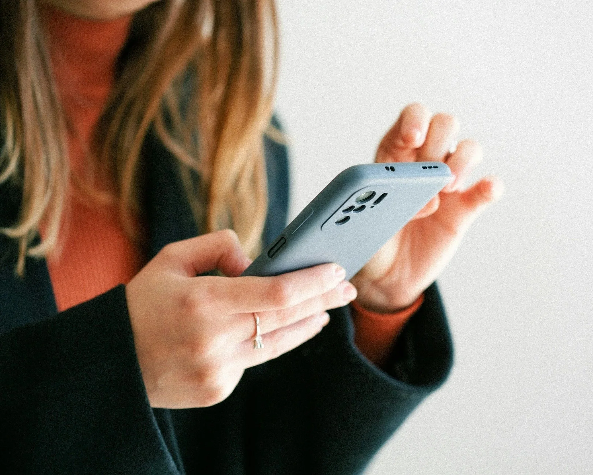 Close-up of a woman holding and using a smartphone in her hands.