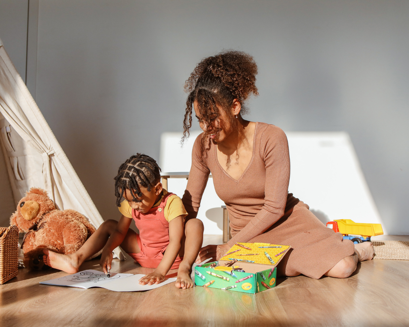 A woman and a young girl sitting on the floor and drawing together, surrounded by toys – representing Elite Sitters & Care Co’s interactive, creative childcare approach for families in DC, Maryland, and Virginia.