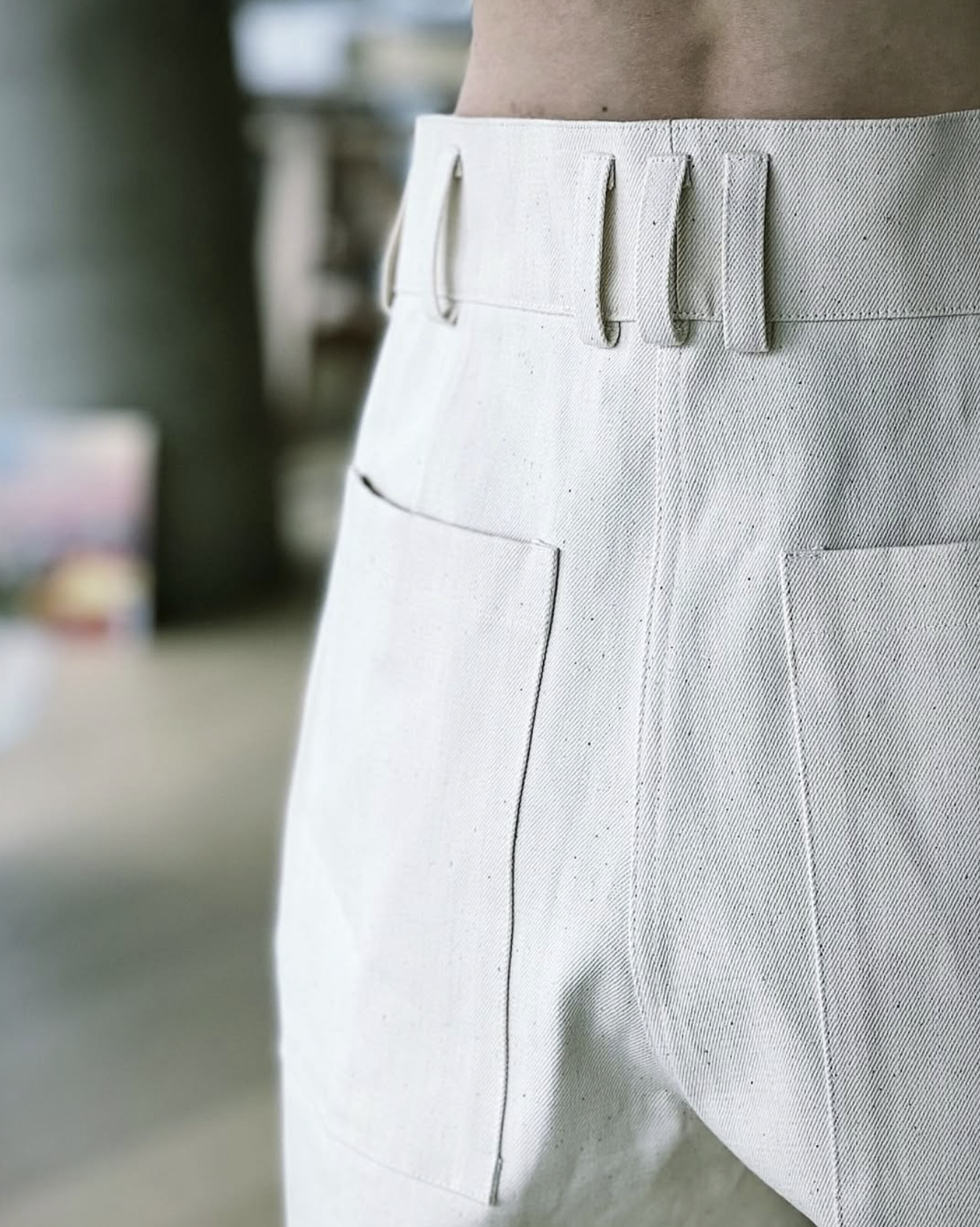 Close-up of white pants with belt loops and back pockets.