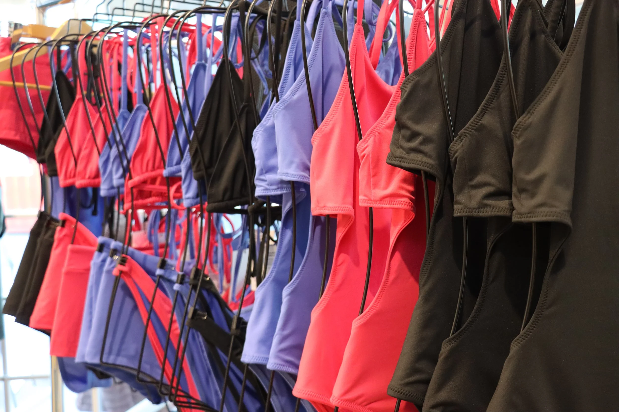 Colorful bikini tops hanging on display at a store.