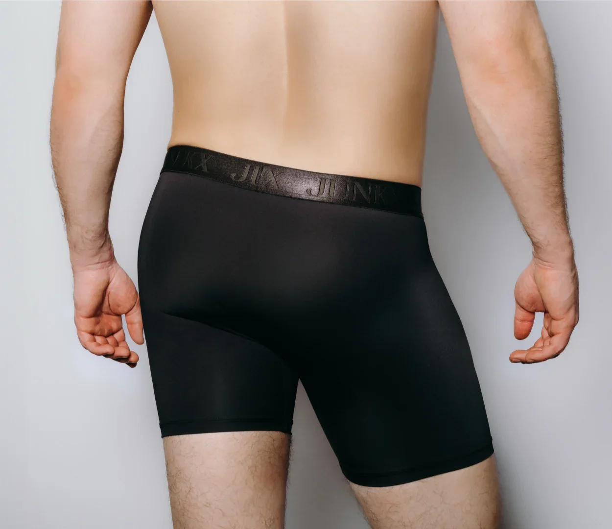 Back view of a man wearing black JX Junk boxer briefs.