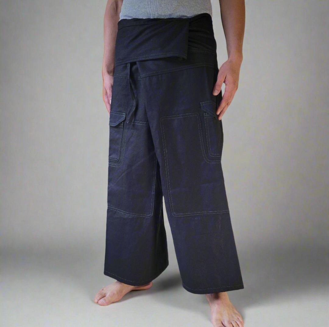 A person standing barefoot, wearing dark wide-leg martial arts pants with a waistband, and a gray T-shirt, against a plain neutral background.