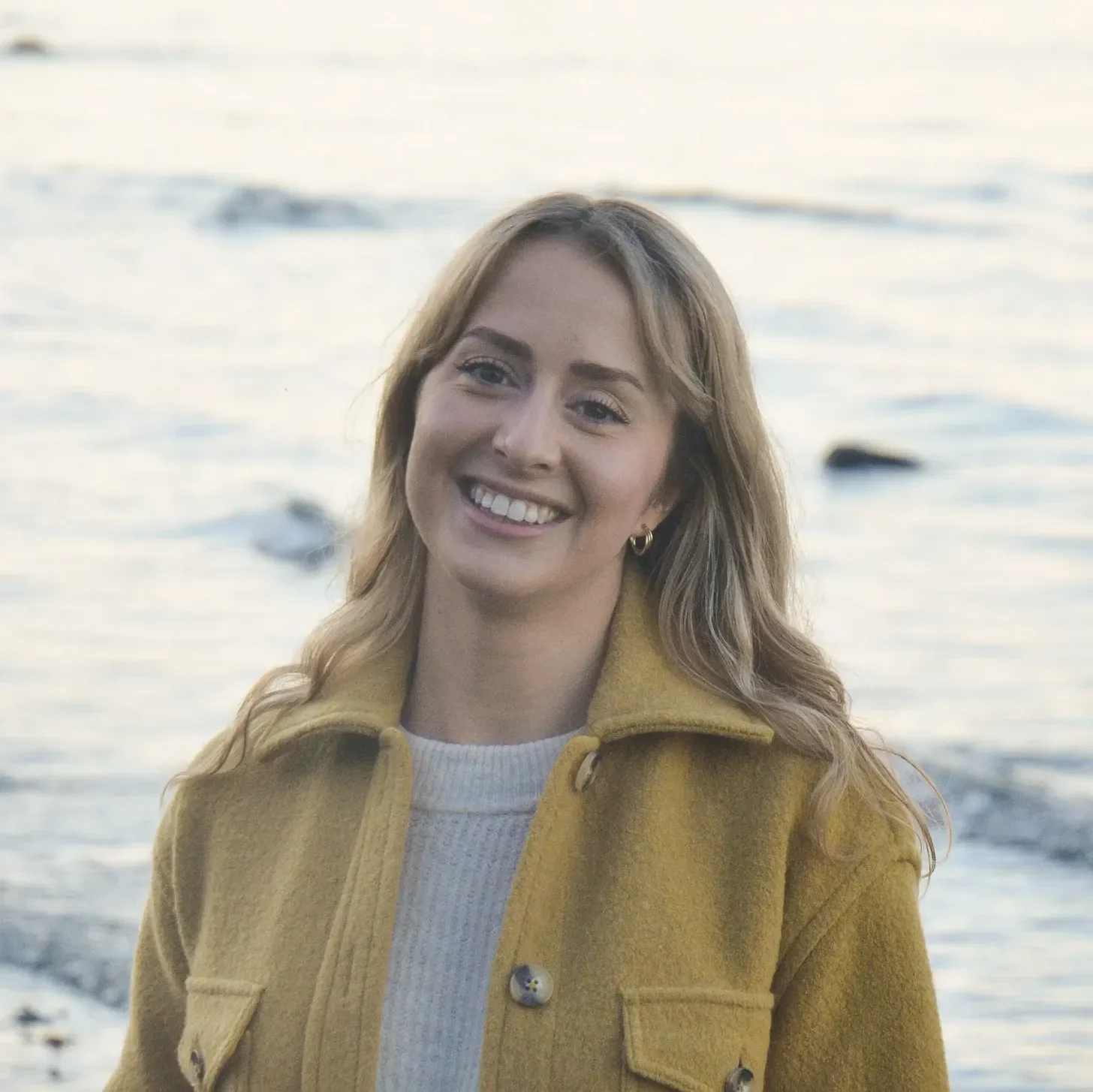 headshot of fleck creative studio founder, Jazmin Welch, standing in front of the ocean