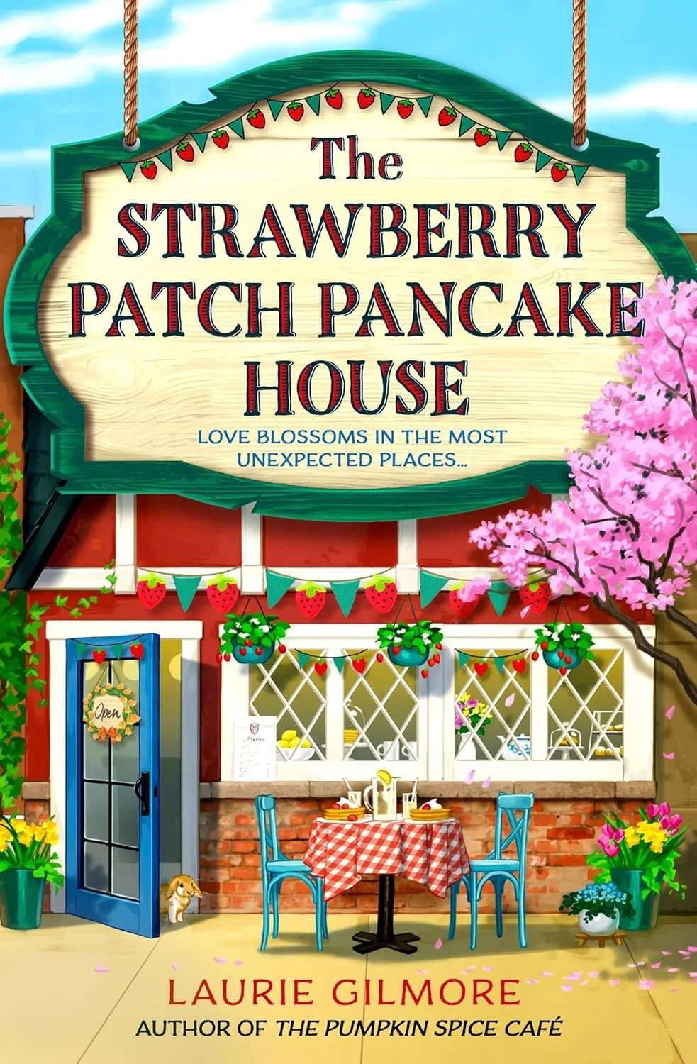 Colorful illustrated storefront of The Strawberry Patch Pancake House with outdoor seating, pink cherry blossom tree, and spring flowers, featuring a sign that reads 'Love blossoms in the most unexpected places...' and author Laurie Gilmore's name at