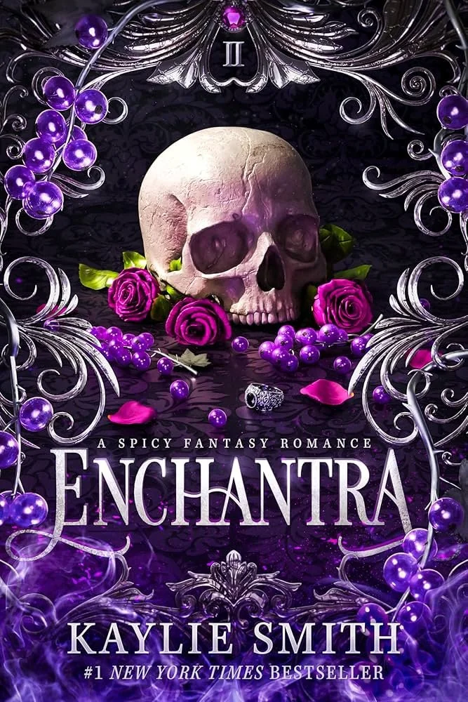 Book cover for "Enchantra" by Kaylie Smith featuring a human skull surrounded by purple roses, grapes, and a ring, with elegant silver flourish designs and the tagline "A Spicy Fantasy Romance."