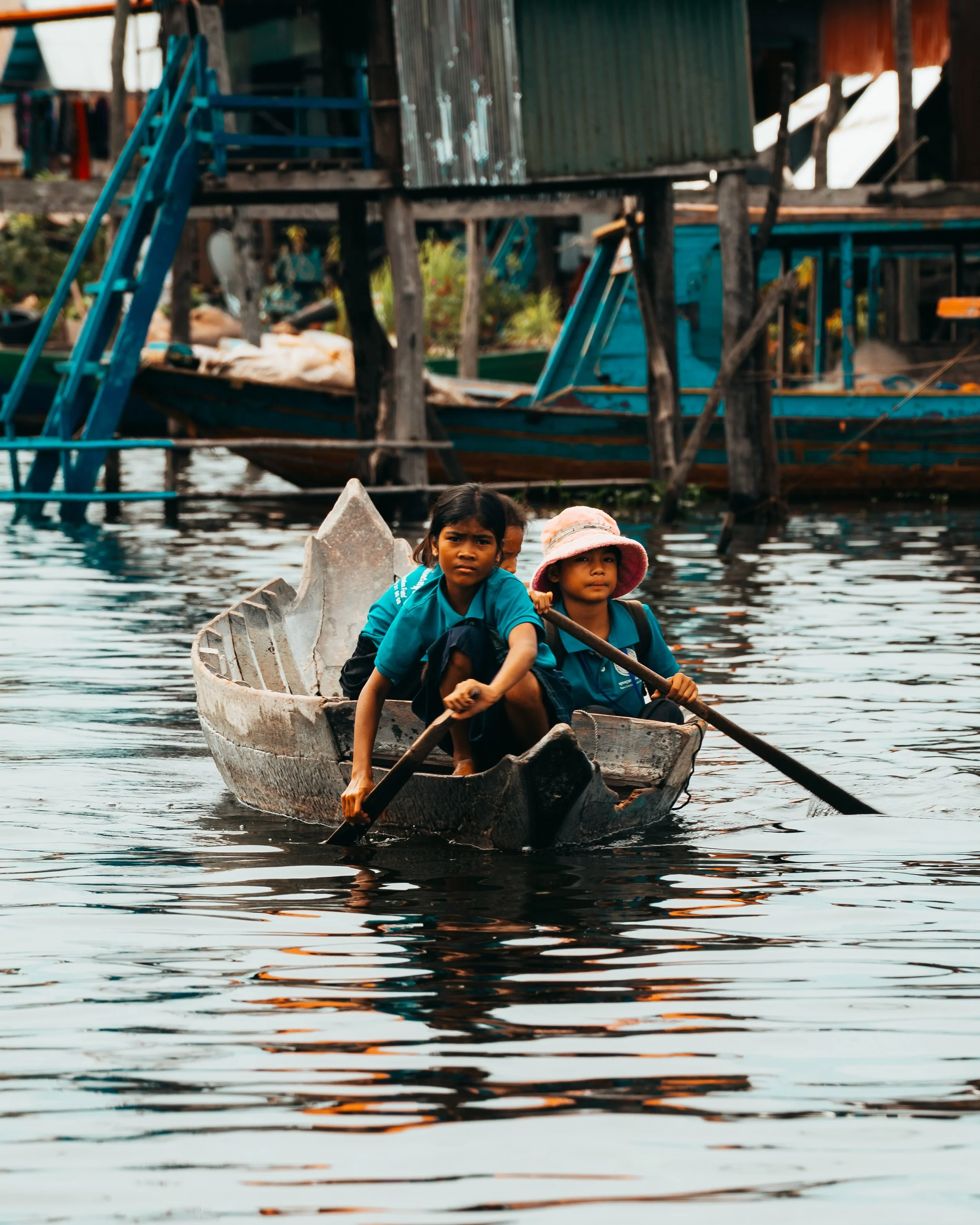 Local school children rowing boats home in the village of Kompong Phluk, Cambodia