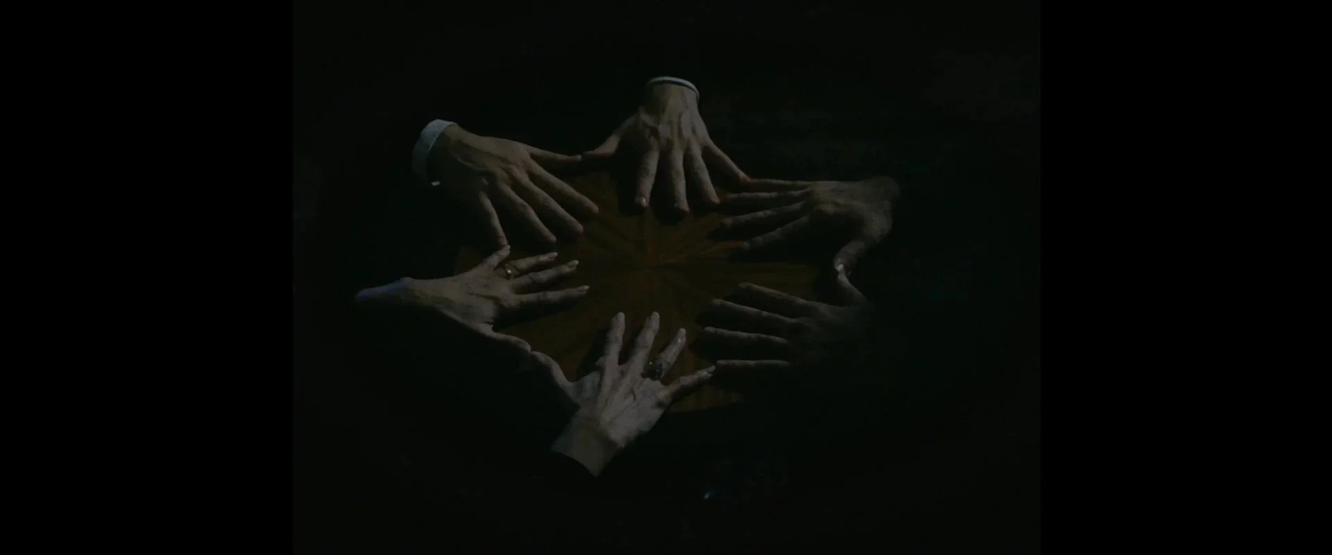 Multiple hands reaching towards a central star-shaped wooden surface on a dark background.