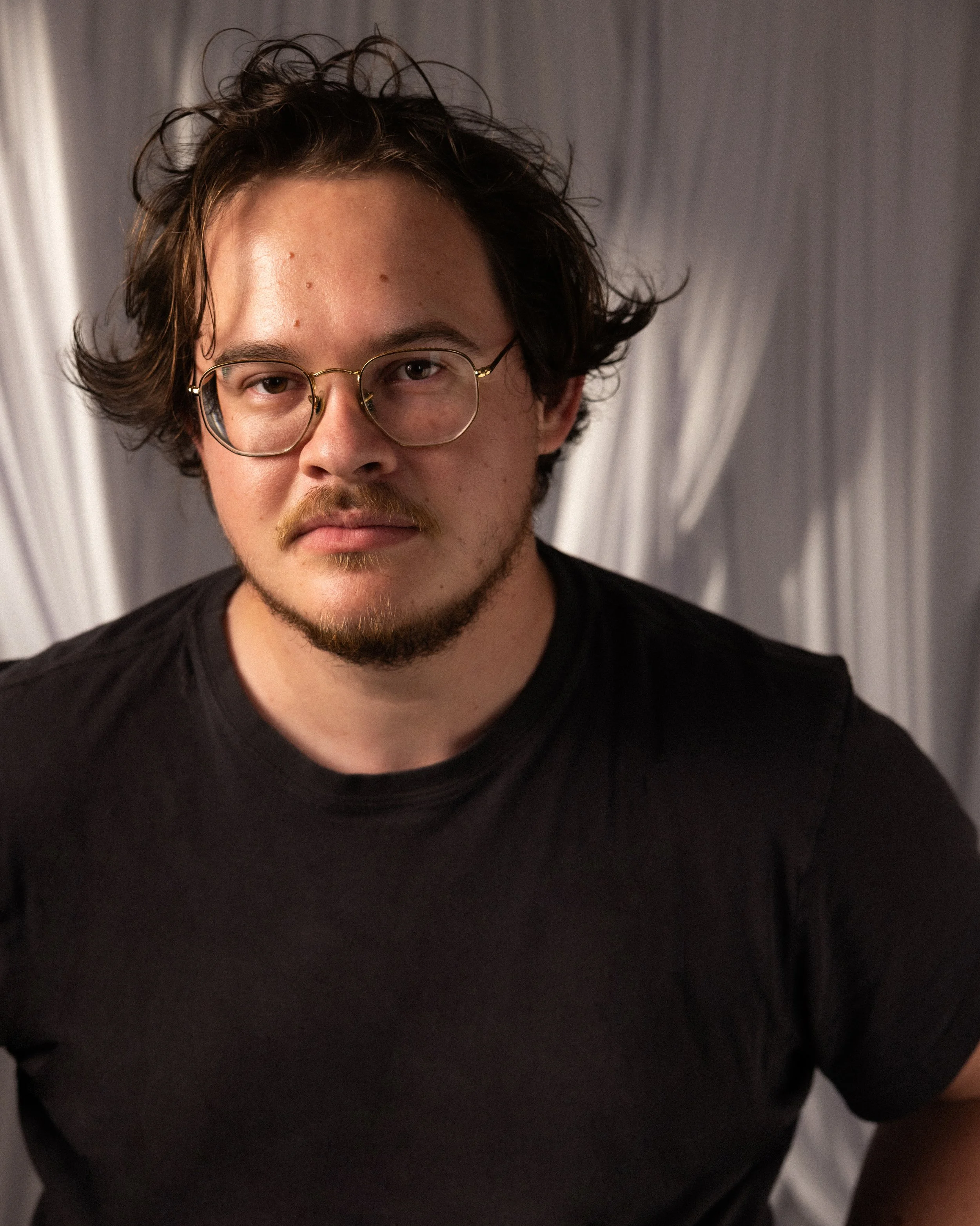 A man with short hair and glasses wearing a black shirt.