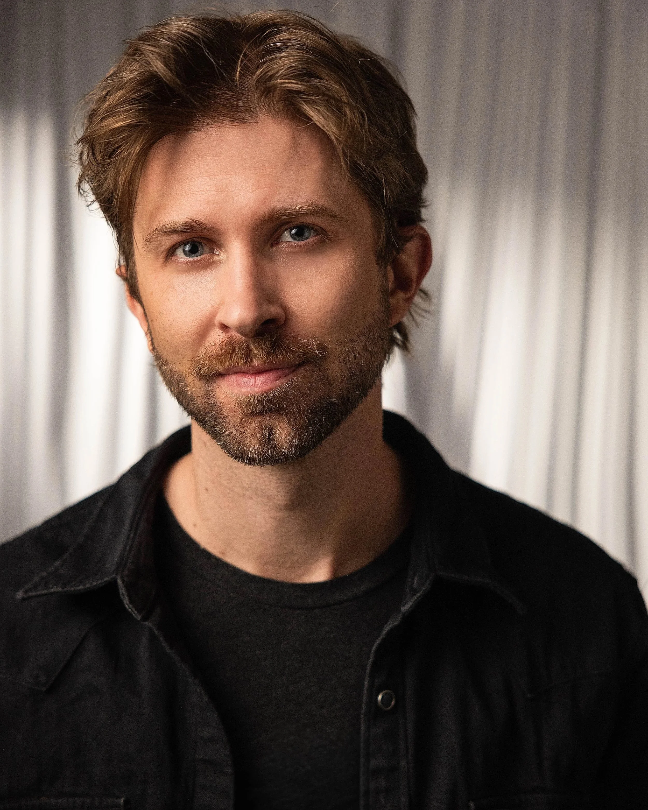 A man with blonde hair and a beard smiling.