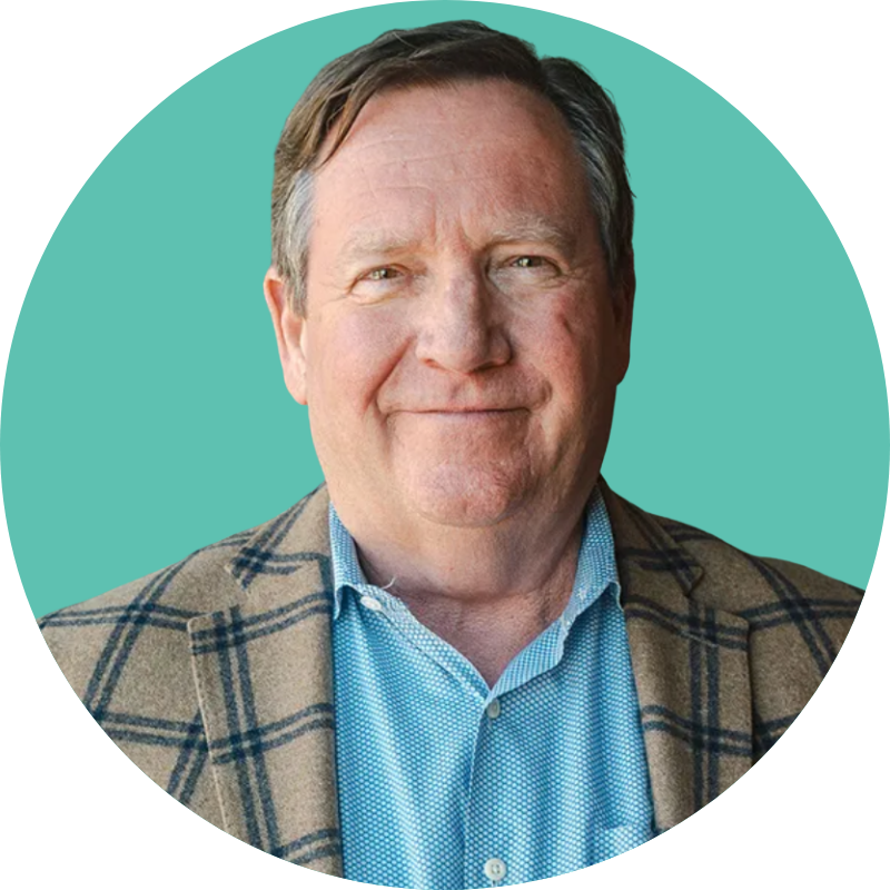 Portrait of a middle-aged man with light brown hair, wearing a blue dress shirt and a brown plaid blazer, smiling against a teal background.