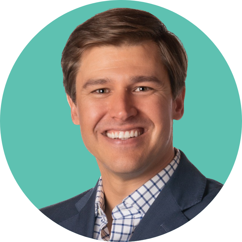 A professional headshot of a smiling man with short brown hair, wearing a dark blazer and a checkered dress shirt, against a teal background.