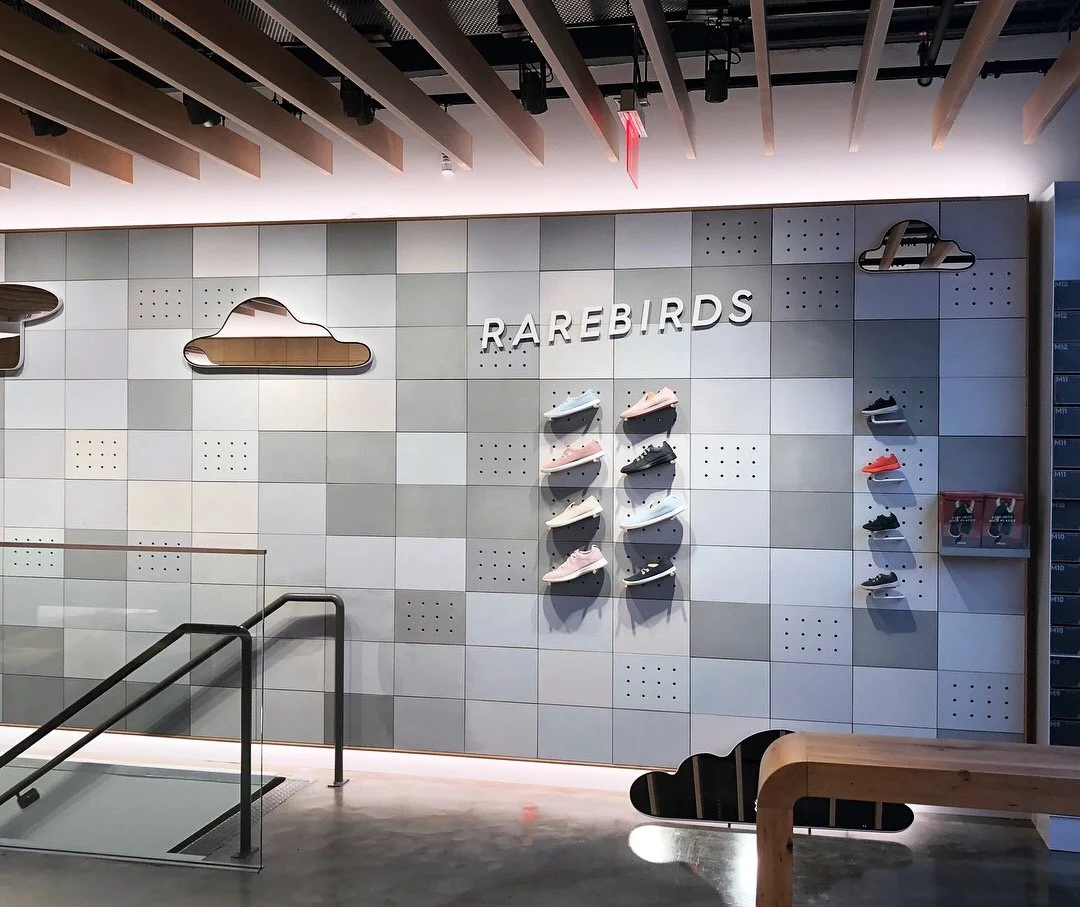 Display wall with shoes arranged on shelves, clouds, and the word "RAREBIRDS" in a modern store interior.