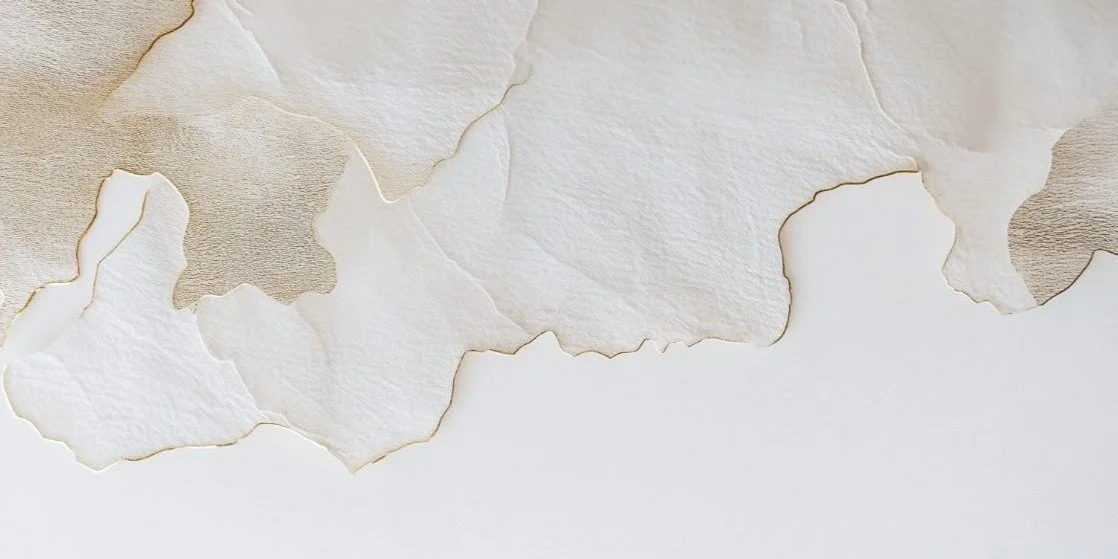 Sheet of torn textured paper in beige and white tones with torn edges.