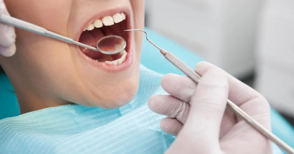 Dentist using a dental mirror and explorer during a comprehensive oral examination.