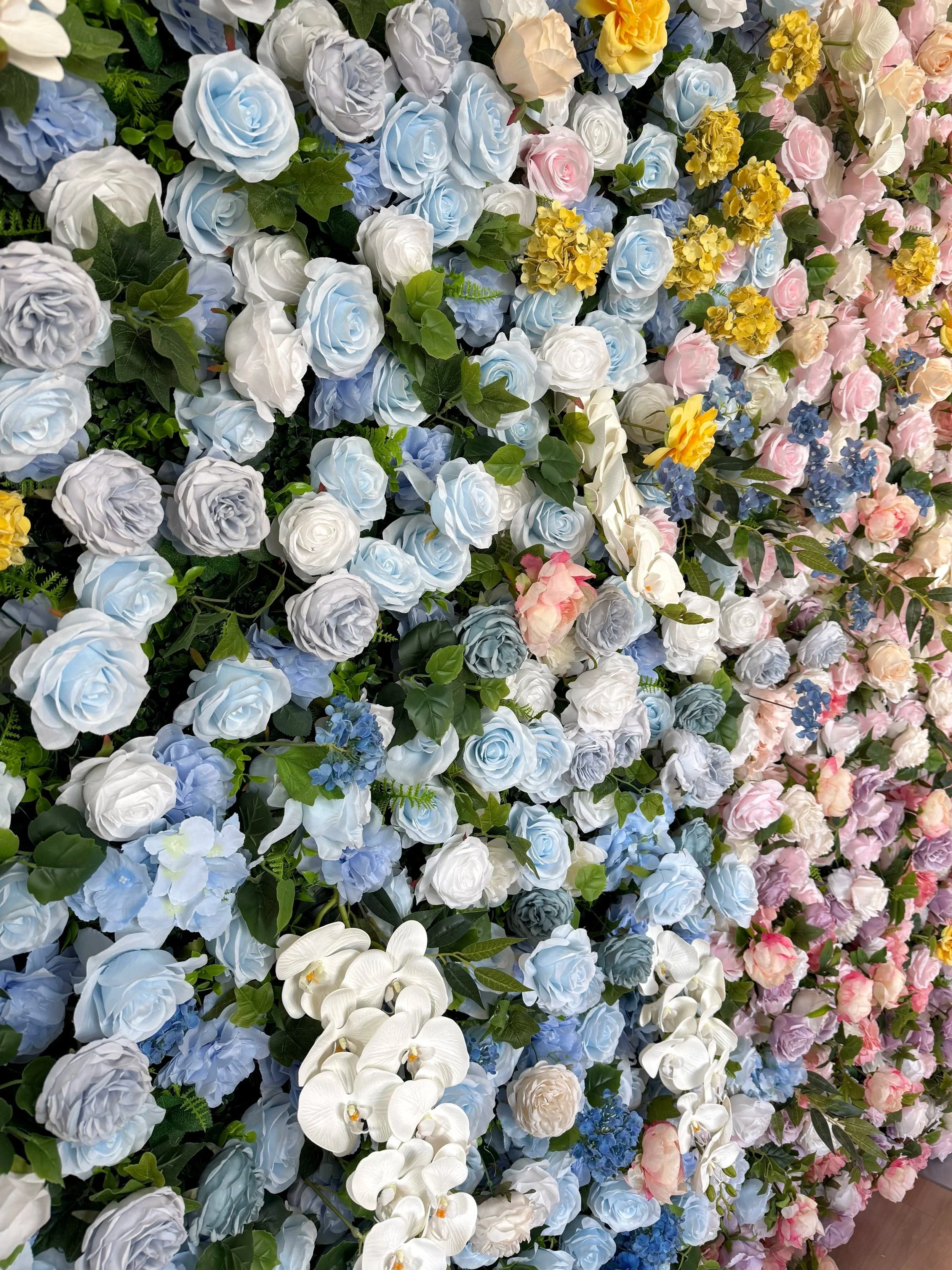 Blue, lavender and blush roses, blue hydrangeas, white orchids, golden blooms, lush greenery.