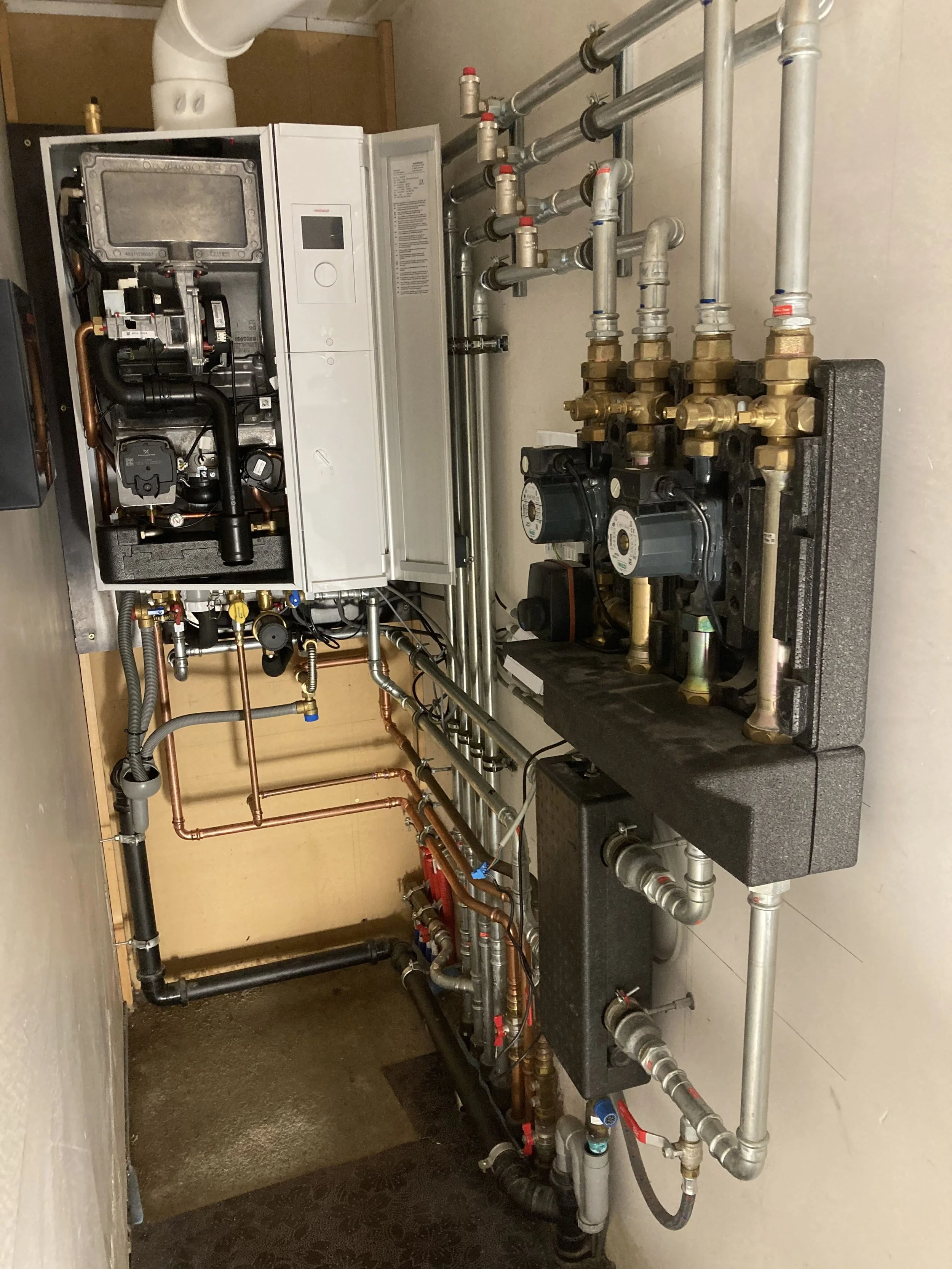 Een cv-ketel en bijbehorende leidingen in een technische ruimte.