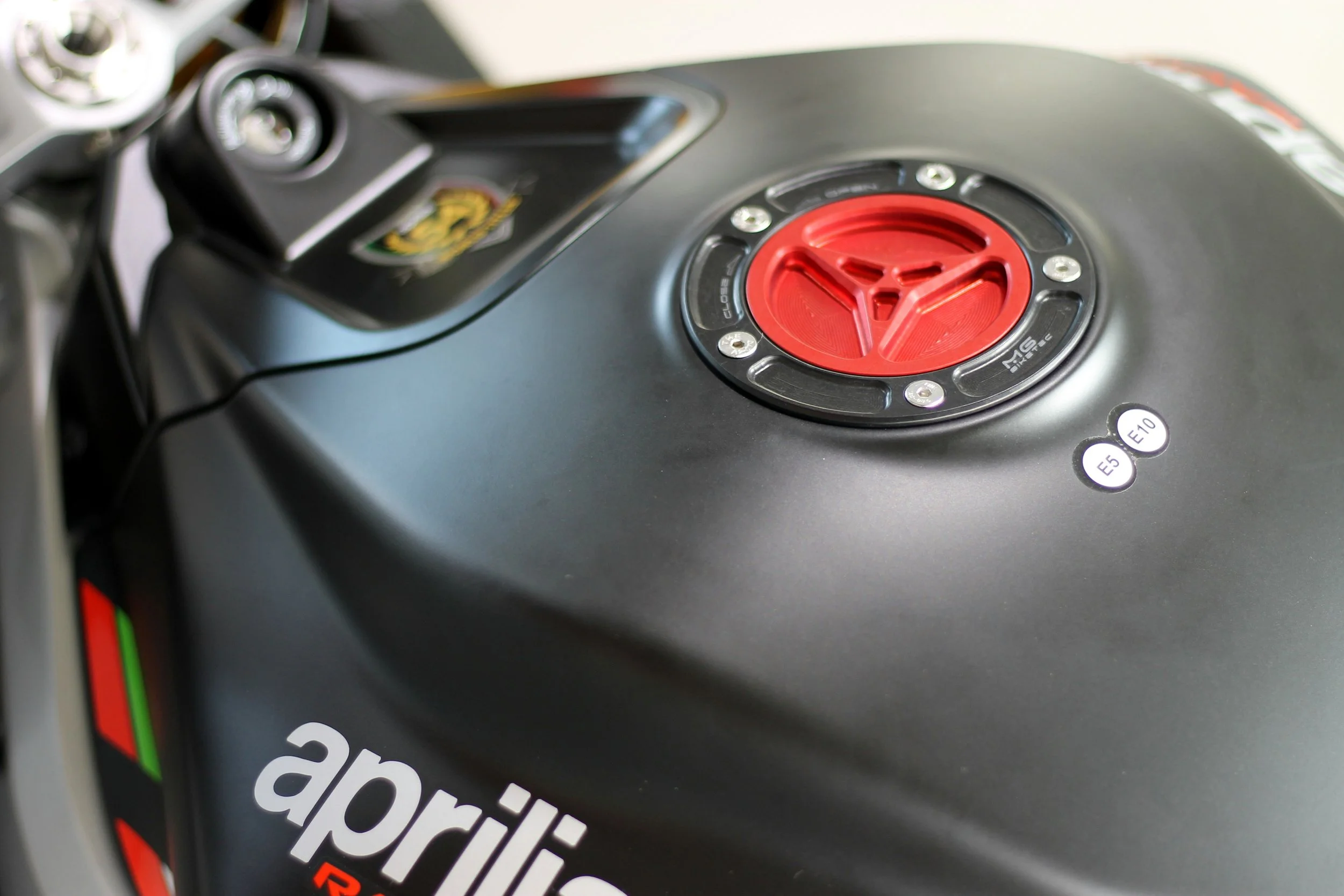 Close-up of a black computer mouse with a red and black logo on it, and a sticker indicating different voltage options (E5, E10).