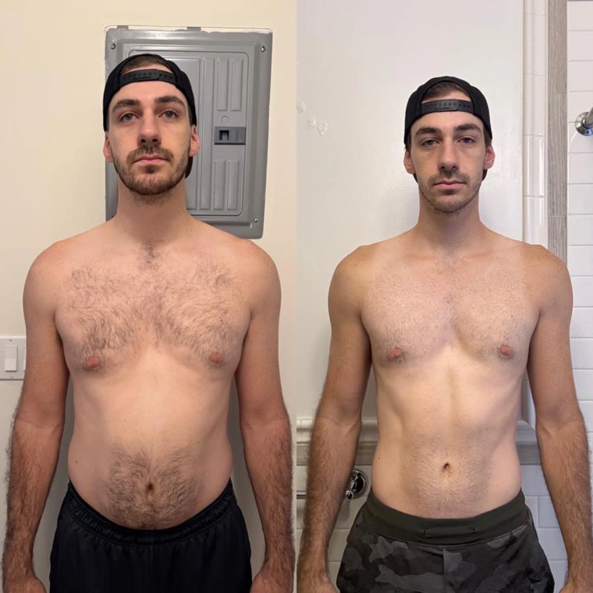 Two young men standing shirtless in a bathroom, side by side, wearing baseball caps backward, with the one on the left wearing black shorts and the one on the right wearing camouflage shorts.