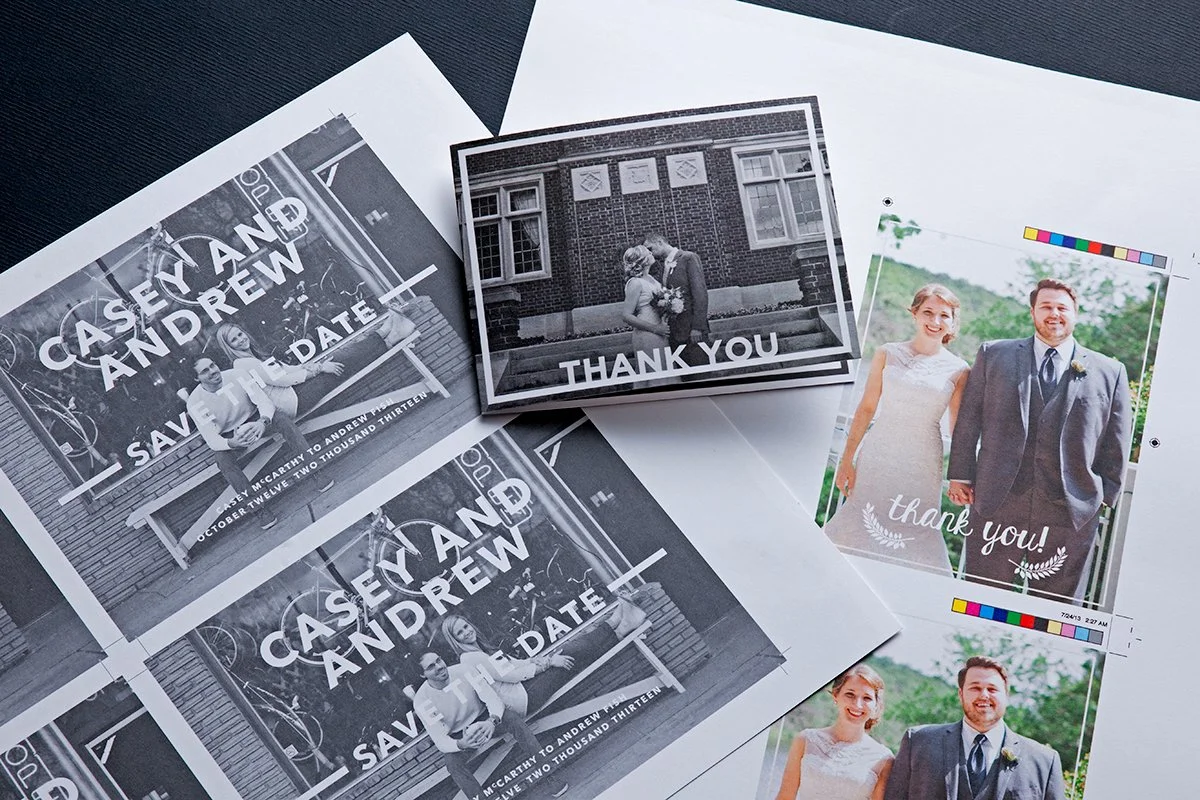 A collection of wedding photos and place cards, including black-and-white photos with the names 'Casey and Andrew' and a color photo of a bride and groom holding hands outdoors.