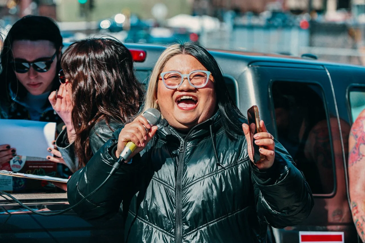 Dieu Do holding a microphone and phone.