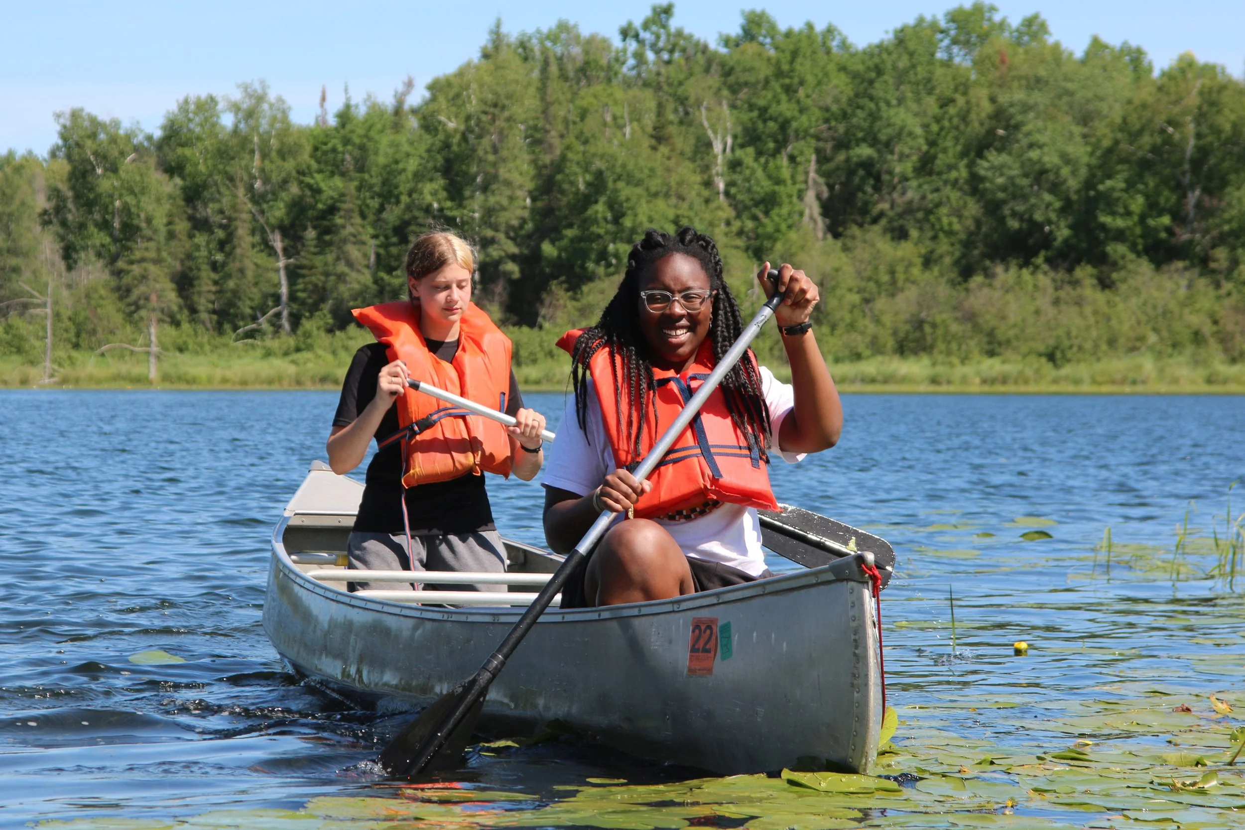 Two girls canoeing in lily pads