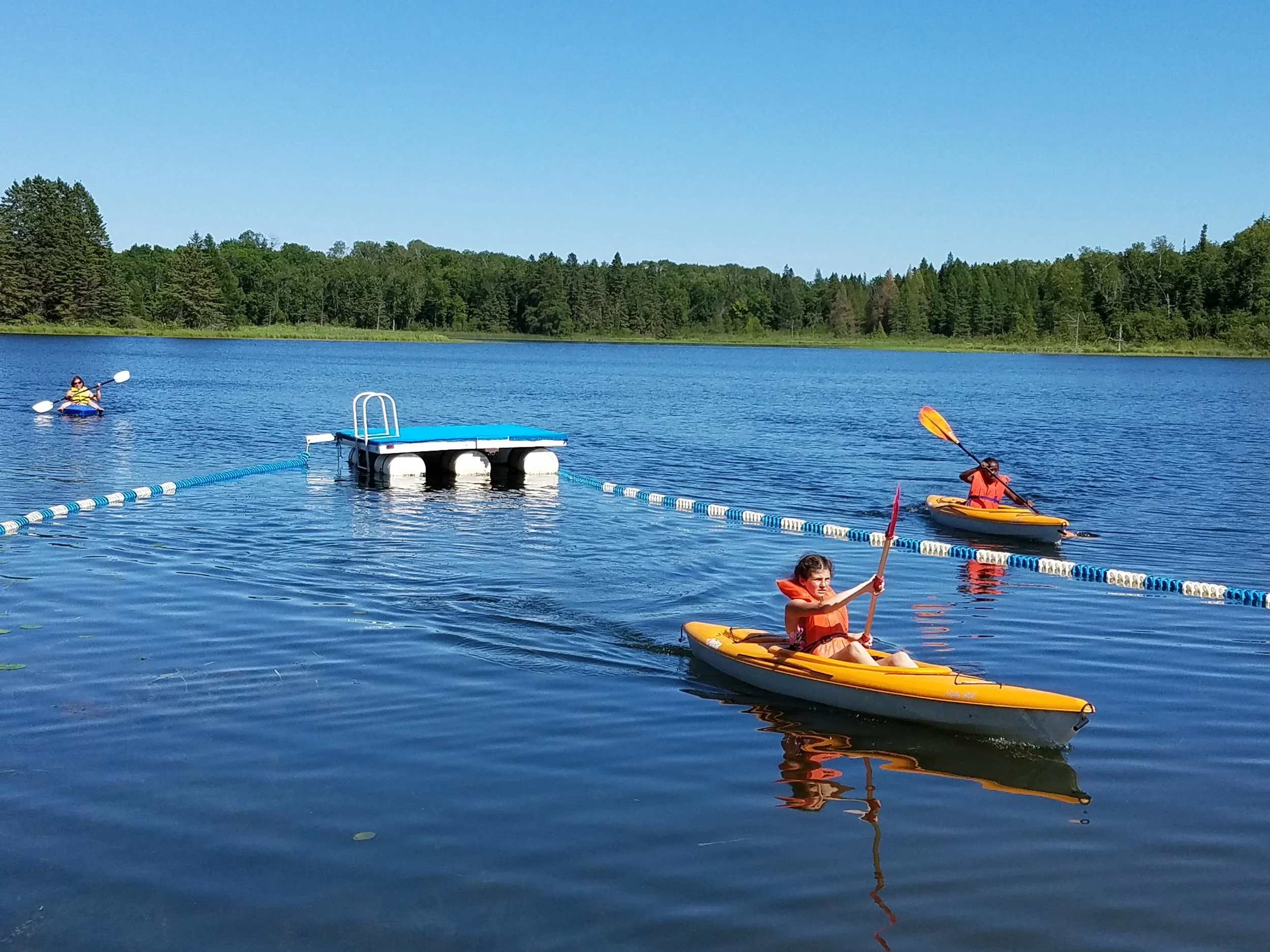 Three kayaks and raft on lake