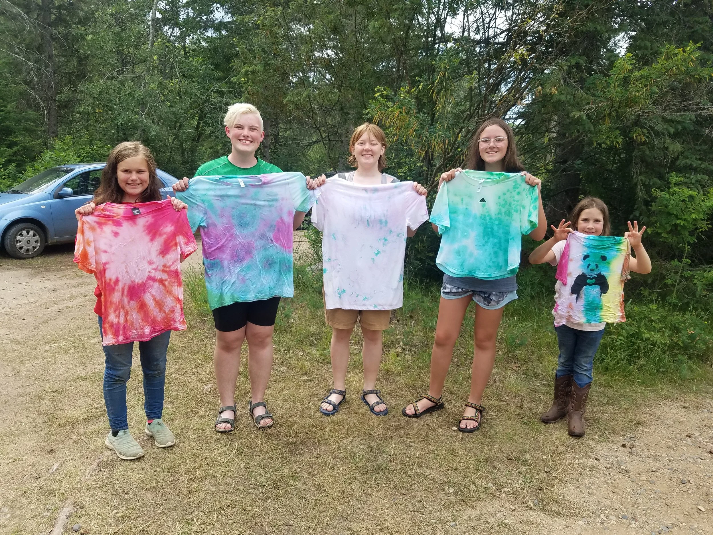 Five girls holding up tie-dye t-shirts